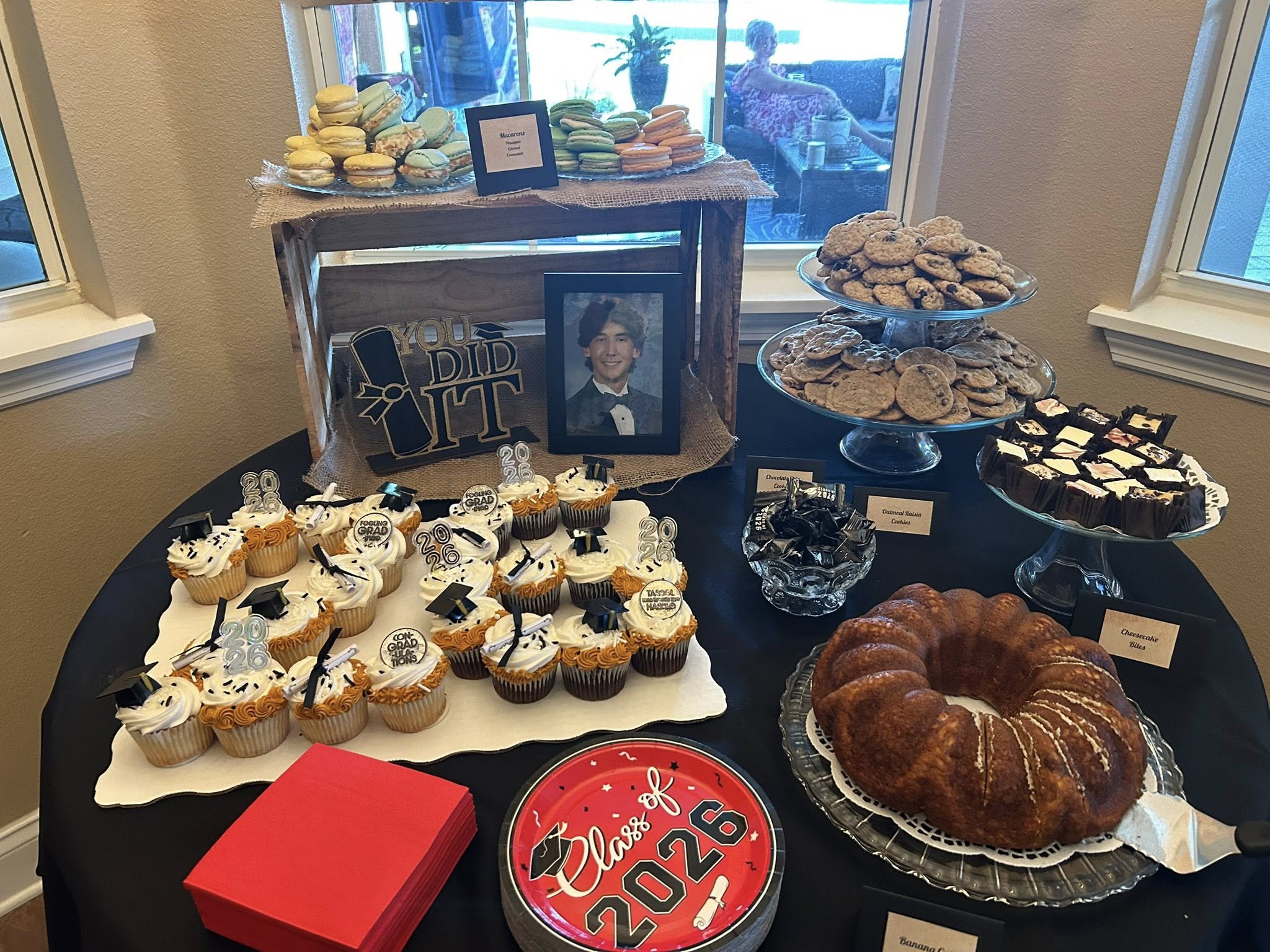 Table spread showcasing a graduation party dessert bar with cupcakes, cookies, macarons, and a bundt cake.