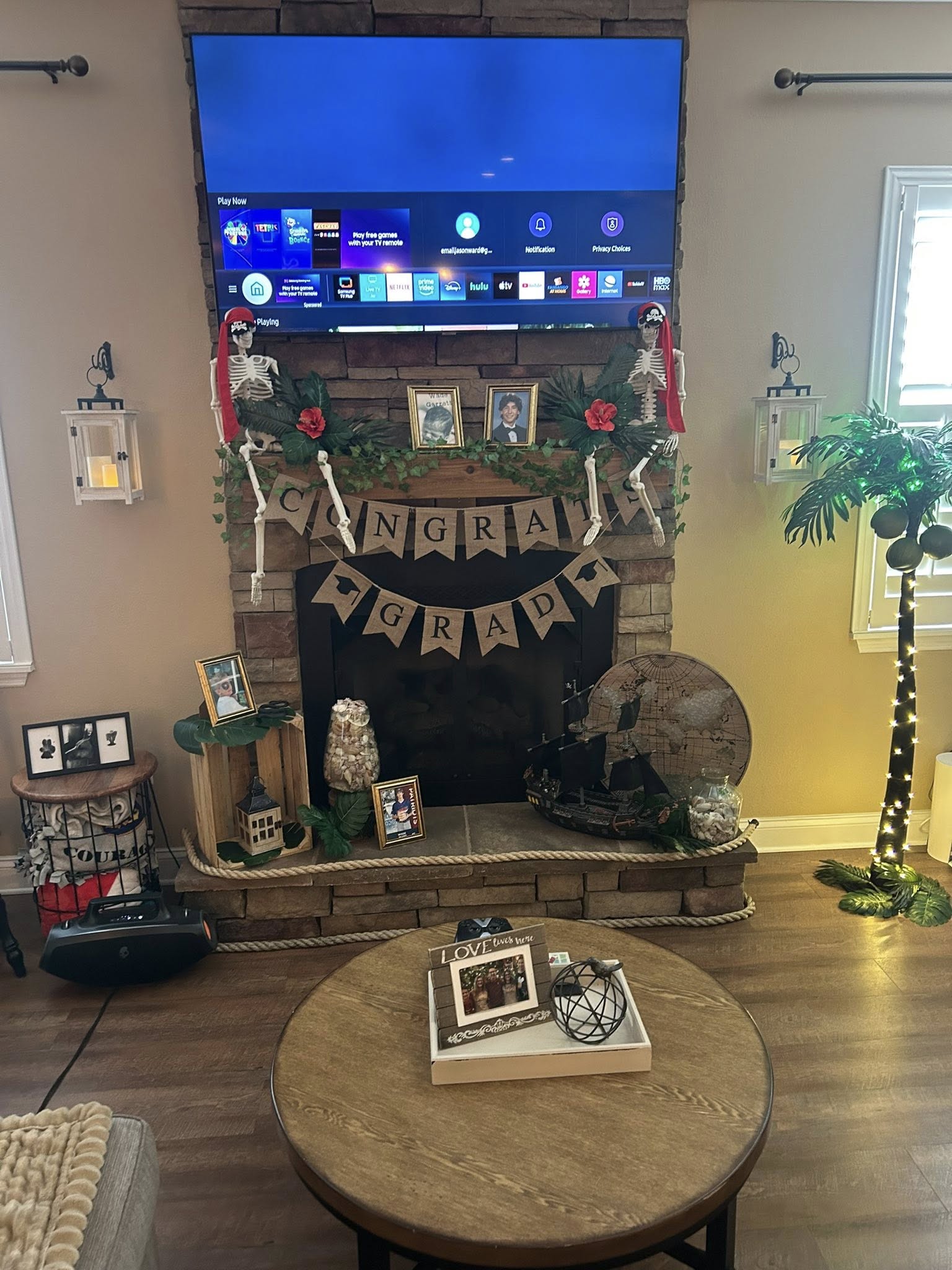 Living room fireplace decorated for a nautical themed graduation party with skeletons, a boat, and congratulatory banner.