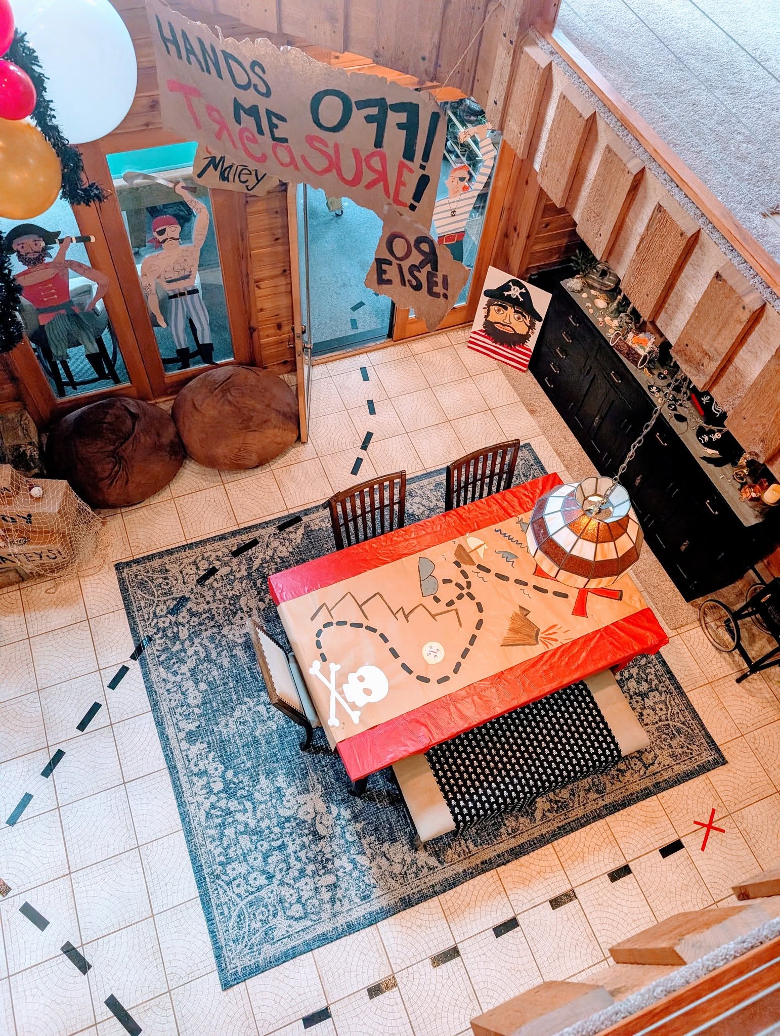 Dining room decorated with a pirate theme, including a treasure map tablecloth and wall signs.