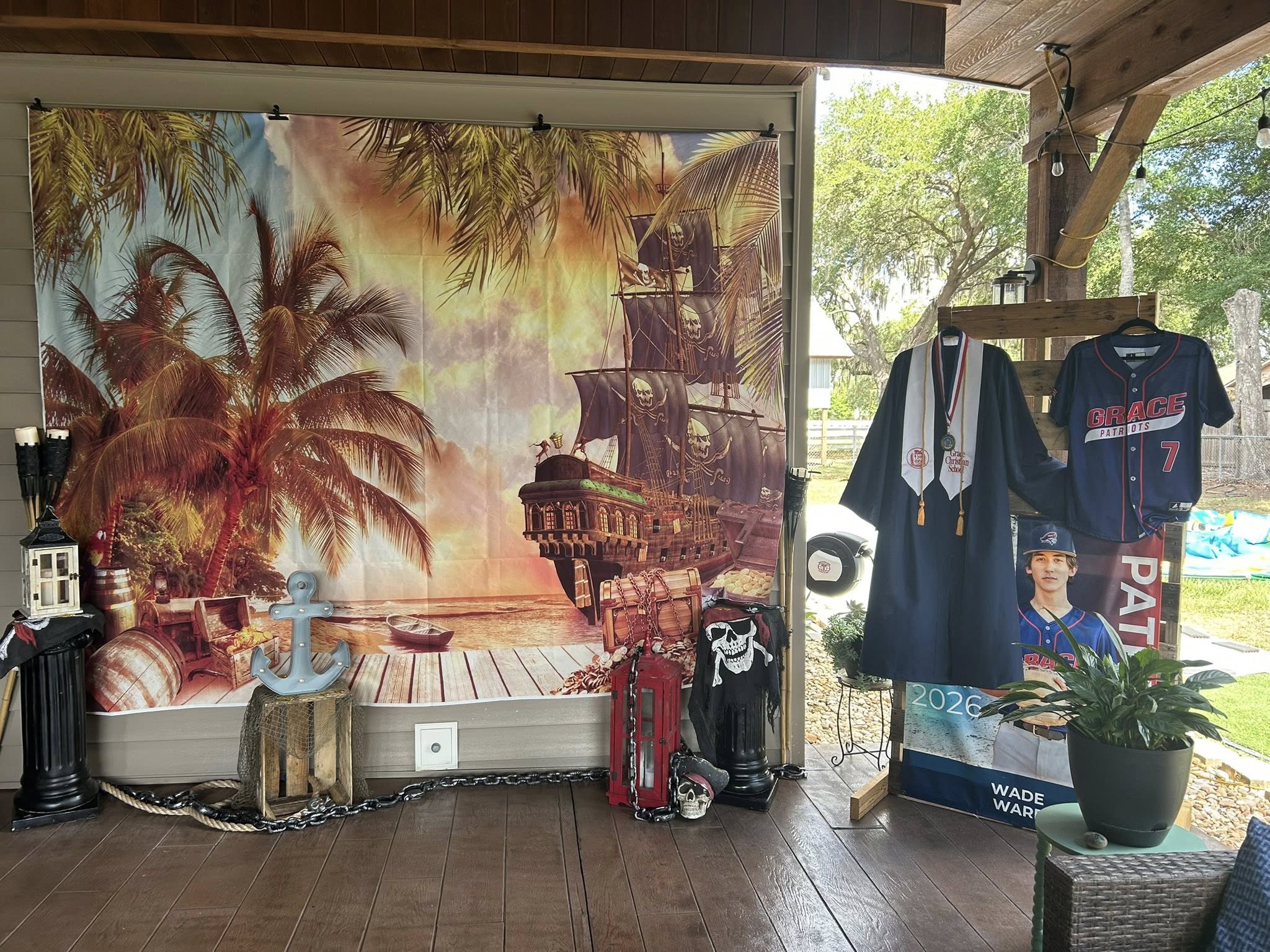 Pirate-themed graduation display featuring a ship backdrop, graduation gown, and Grace Patriots jersey.