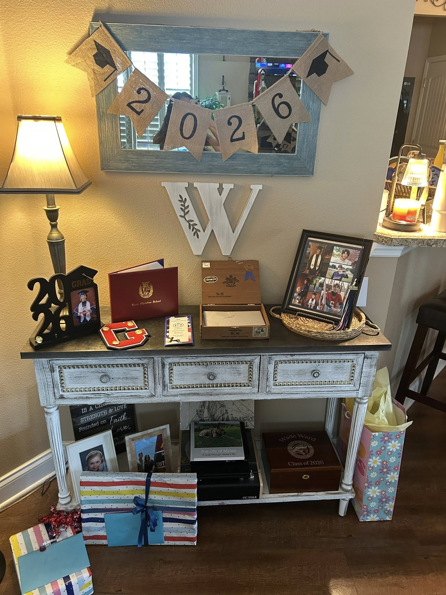 Table decorated with Class of 2026 graduation memorabilia, including photos, a graduation diploma case, and banners.