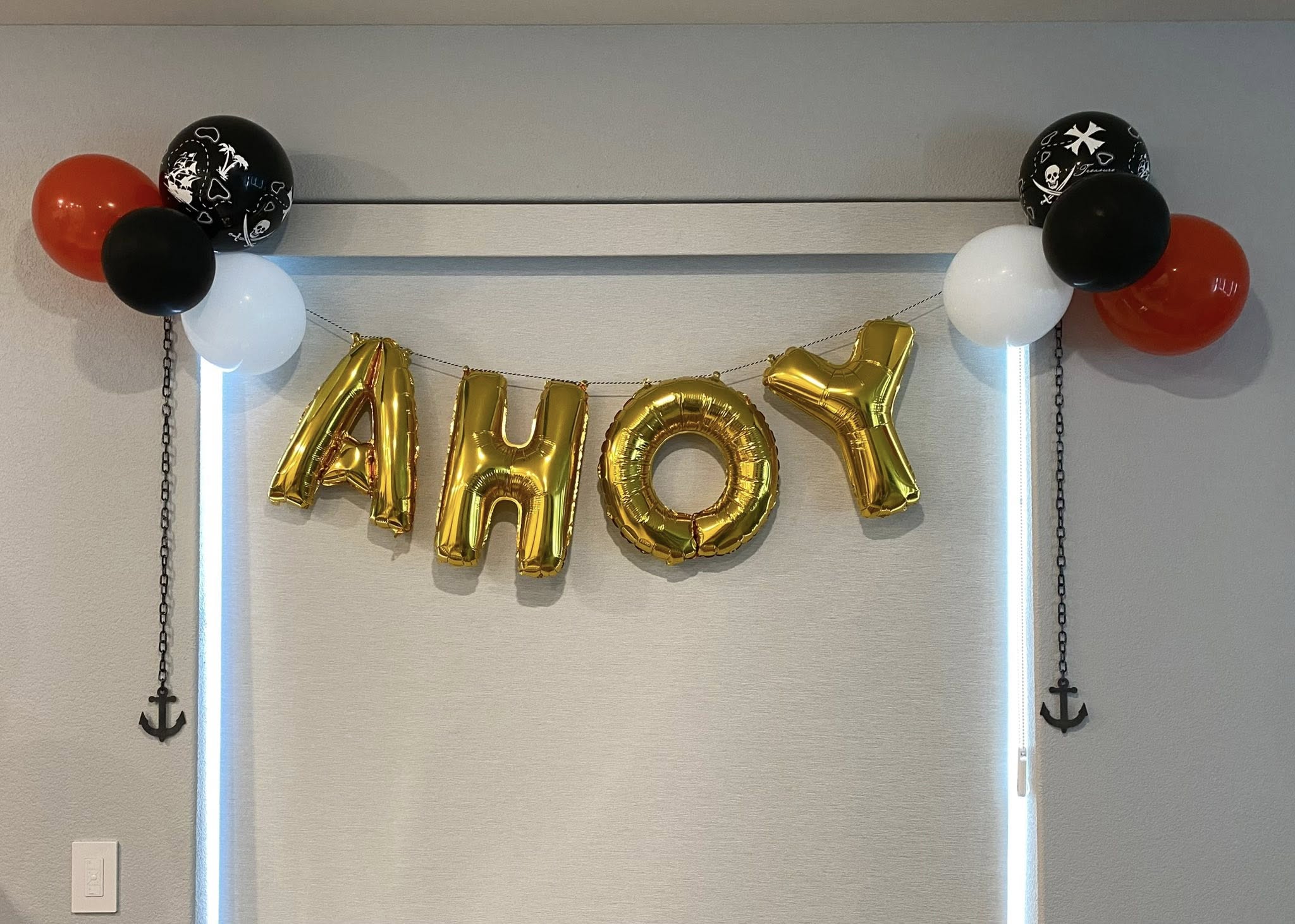 Gold AHOY letter balloons with pirate-themed balloons, black and white accents, and anchor decorations.