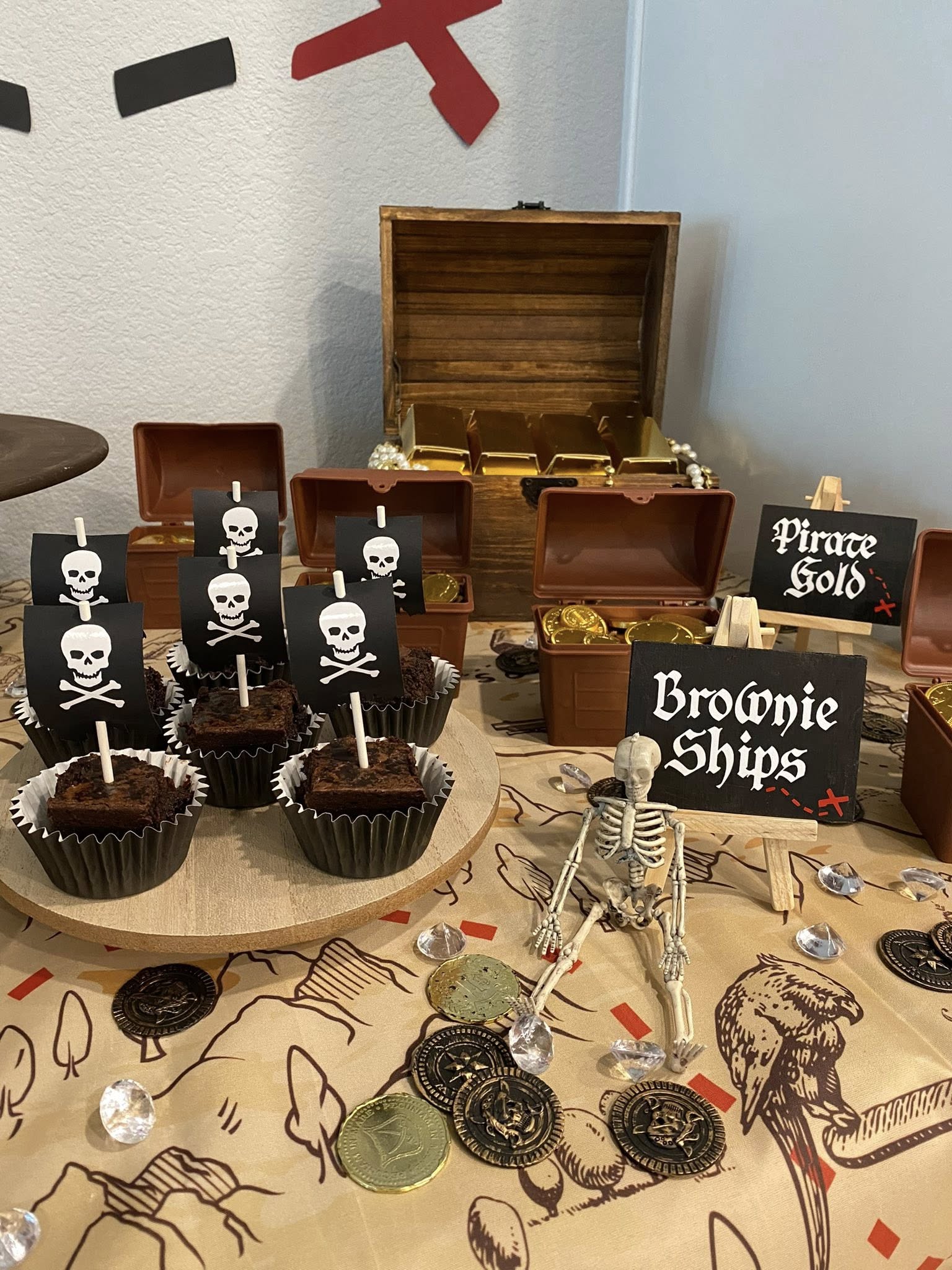Brownie ships with pirate flag toppers displayed on a pirate-themed party table with gold coins and a skeleton.