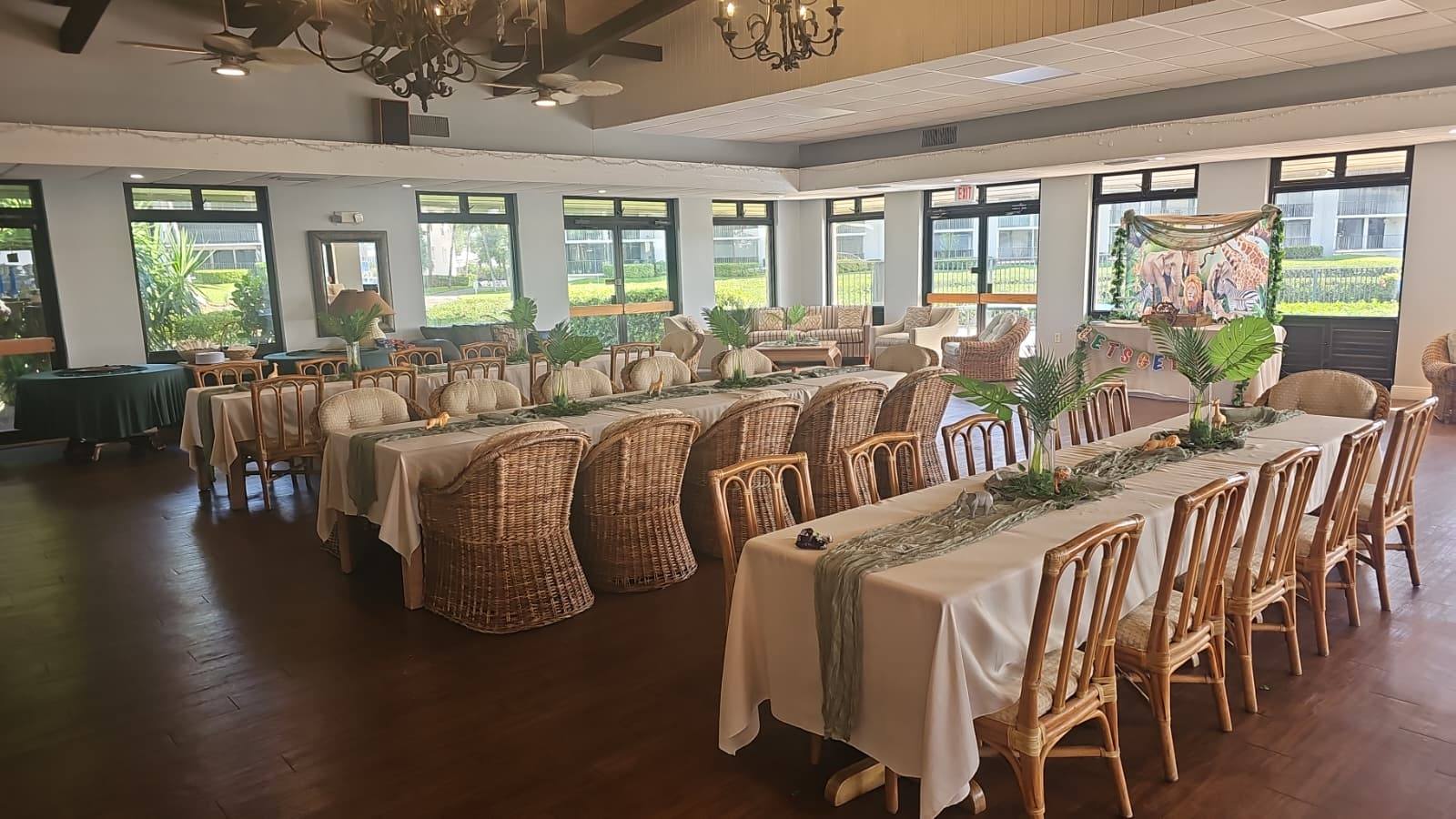 Event space set up with rows of tables, wicker chairs, and jungle-themed decorations.