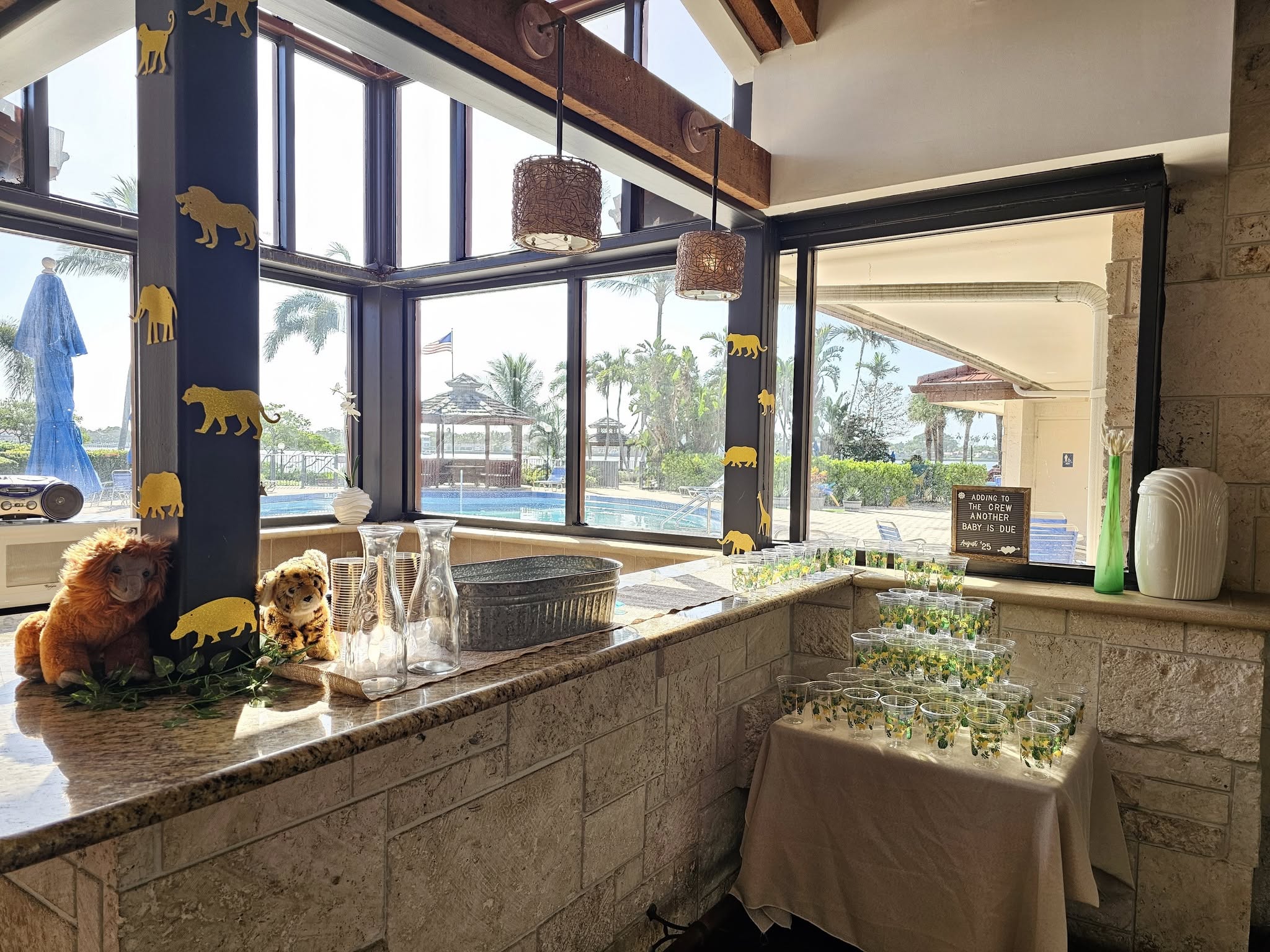 Table at a baby shower with jungle-themed decor, animal cutouts on the wall, and cups for drinks.