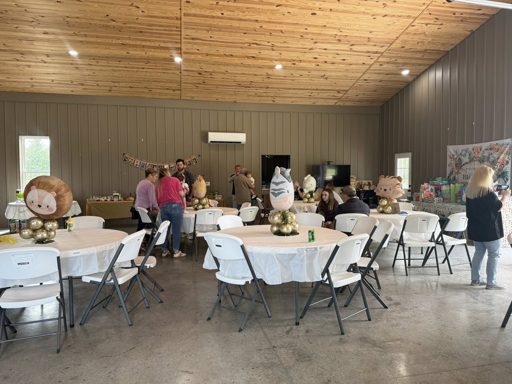 Indoor party venue set up for a baby shower with safari animal theme balloons on round tables