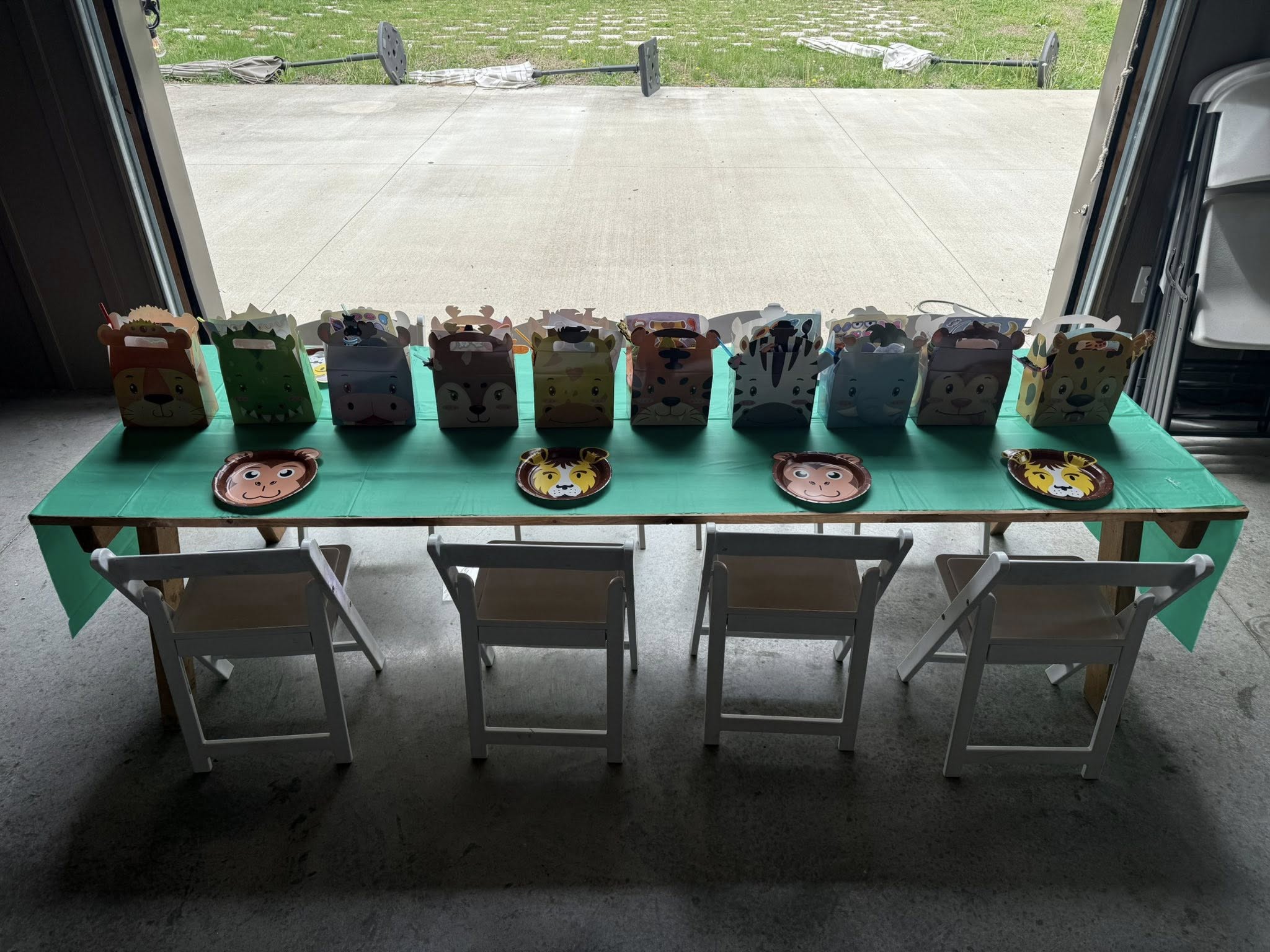 Table set for a safari-themed birthday party with animal-shaped gift boxes and plates.
