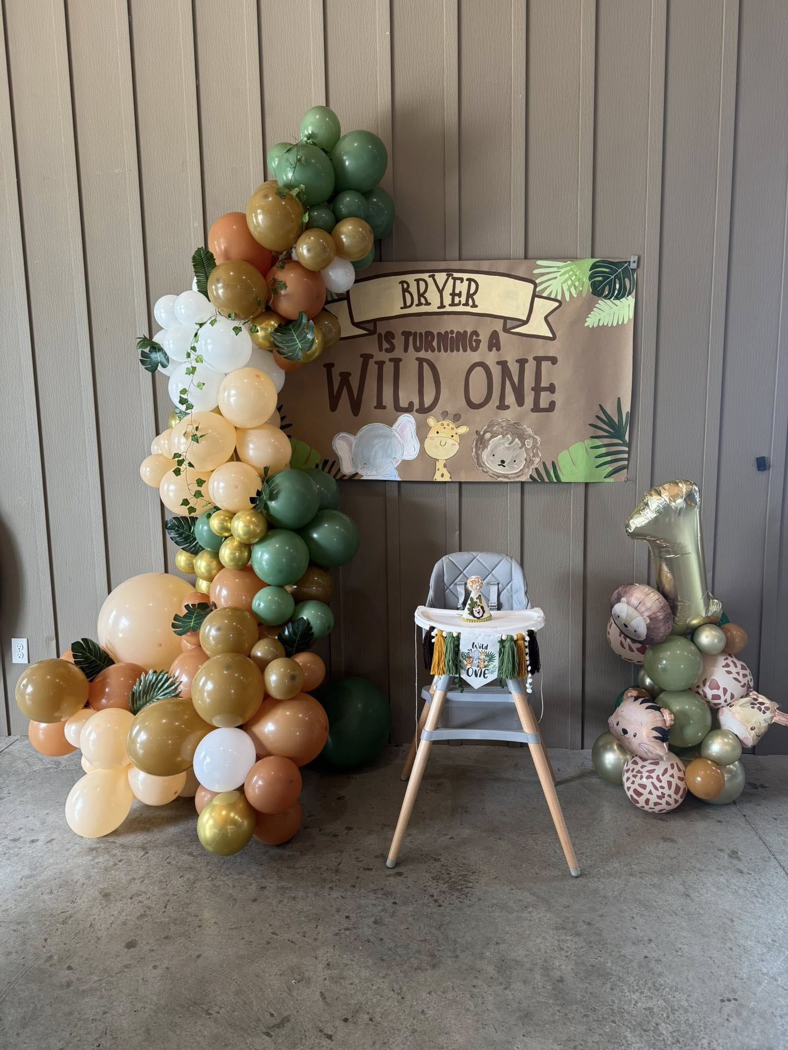 First birthday safari theme high chair set up with balloon garland and Wild One banner.