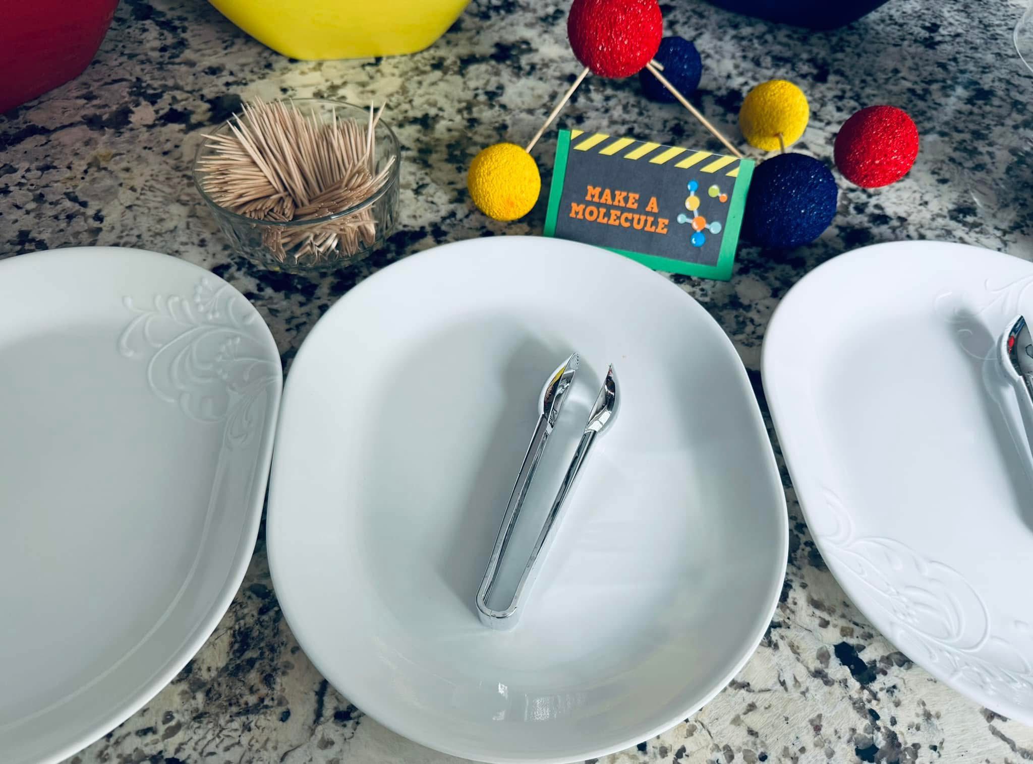 Table setting for a Make a Molecule snack activity featuring toothpicks, colored foam balls, and tongs.