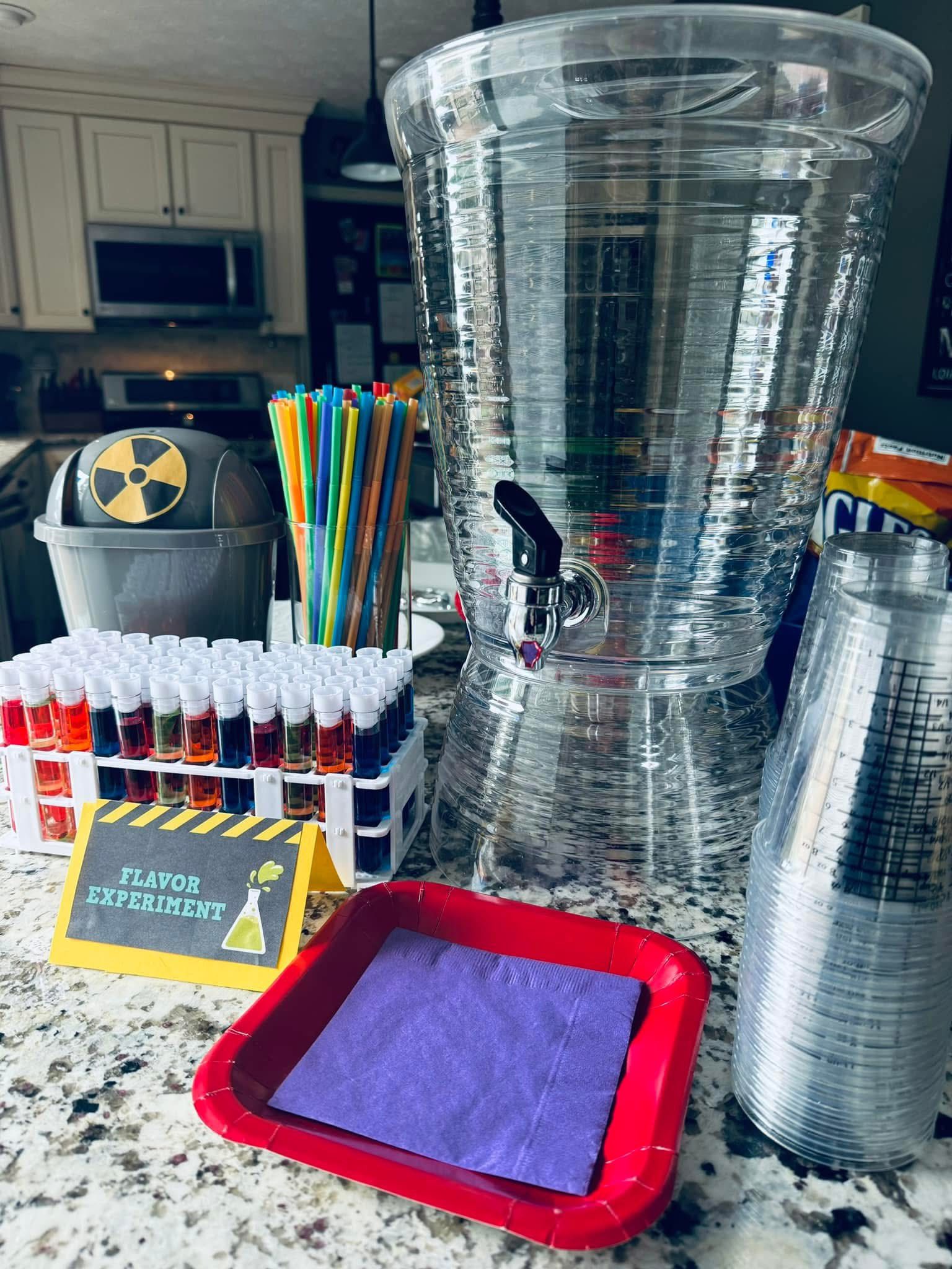 Mad scientist themed drink station featuring colorful test tube drinks, straws, and a large beverage dispenser