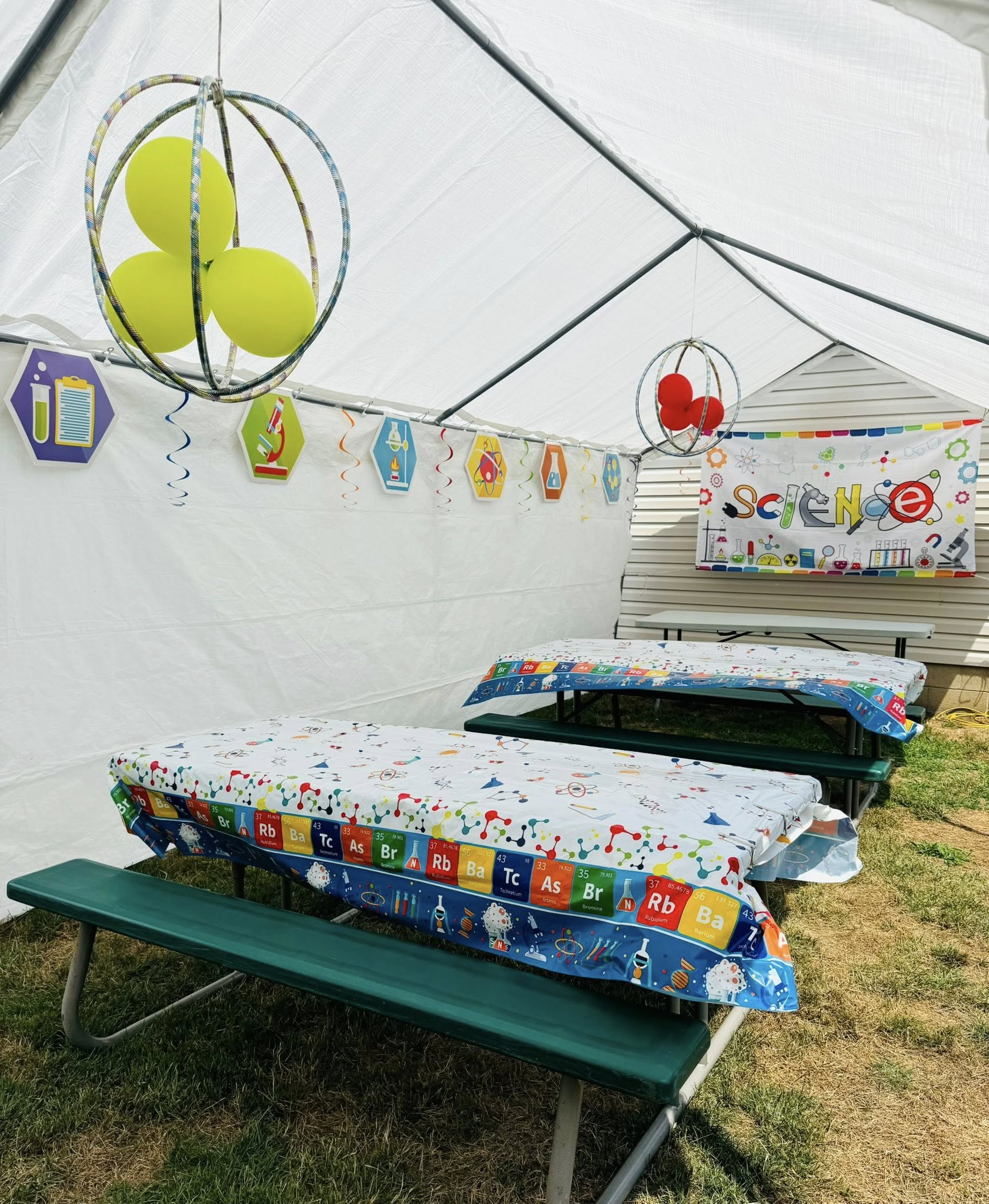 Science-themed birthday party setup with themed tablecloths, hanging atom balloons, and science party decorations.