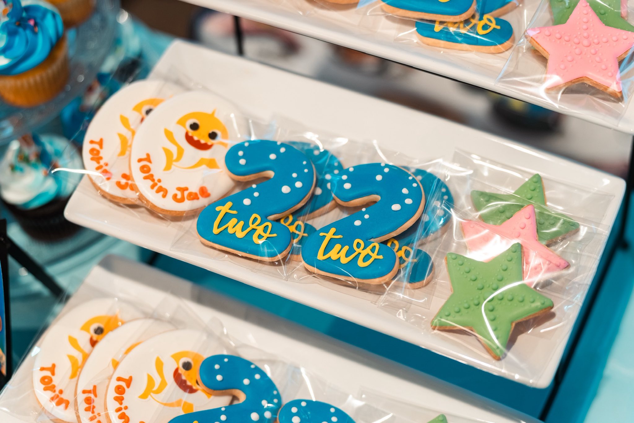 Individually wrapped Baby Shark themed cookies shaped into the number two with blue icing