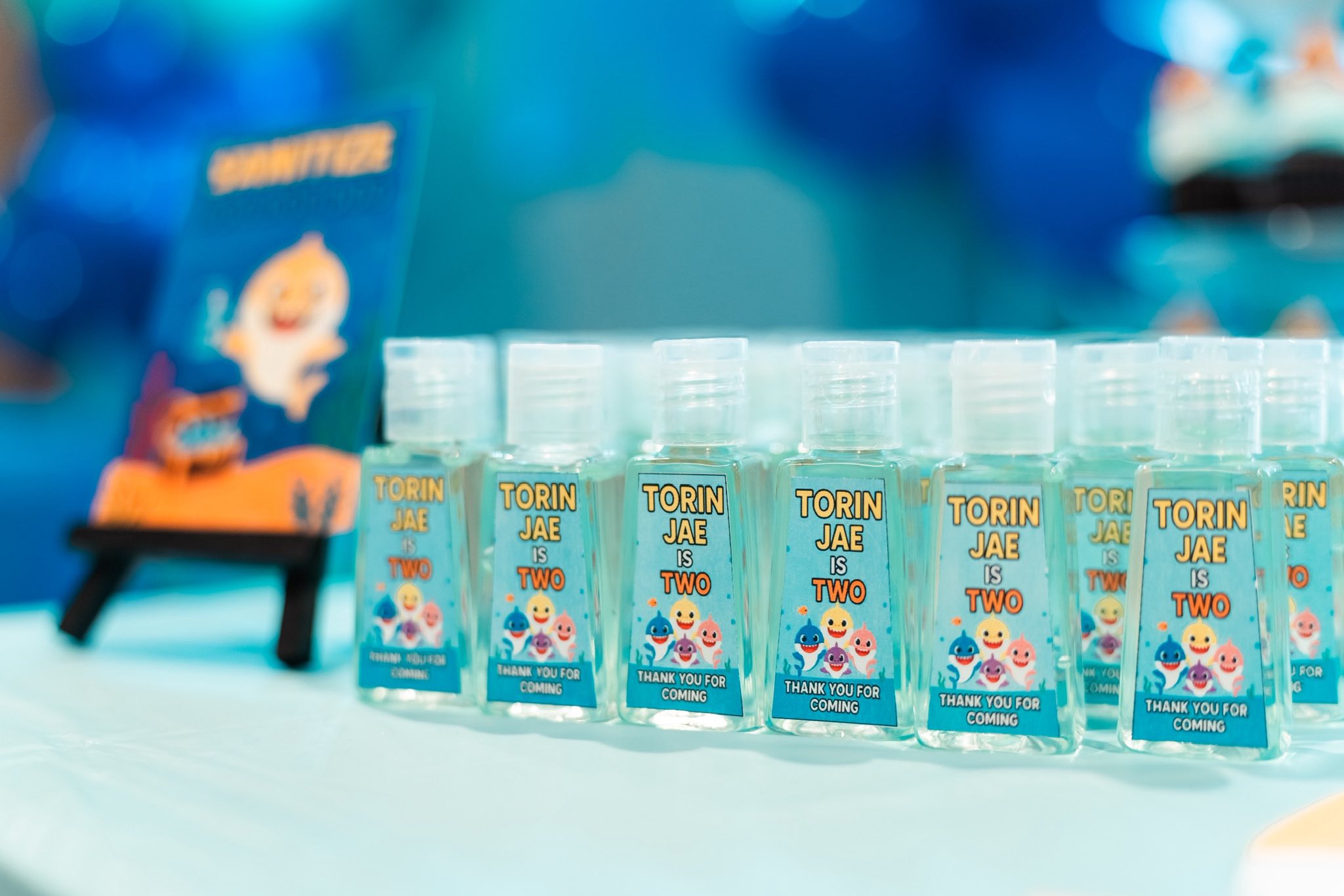 Baby Shark themed bottle of hand sanitizer party favors with personalized label for Torin Jae's second birthday.