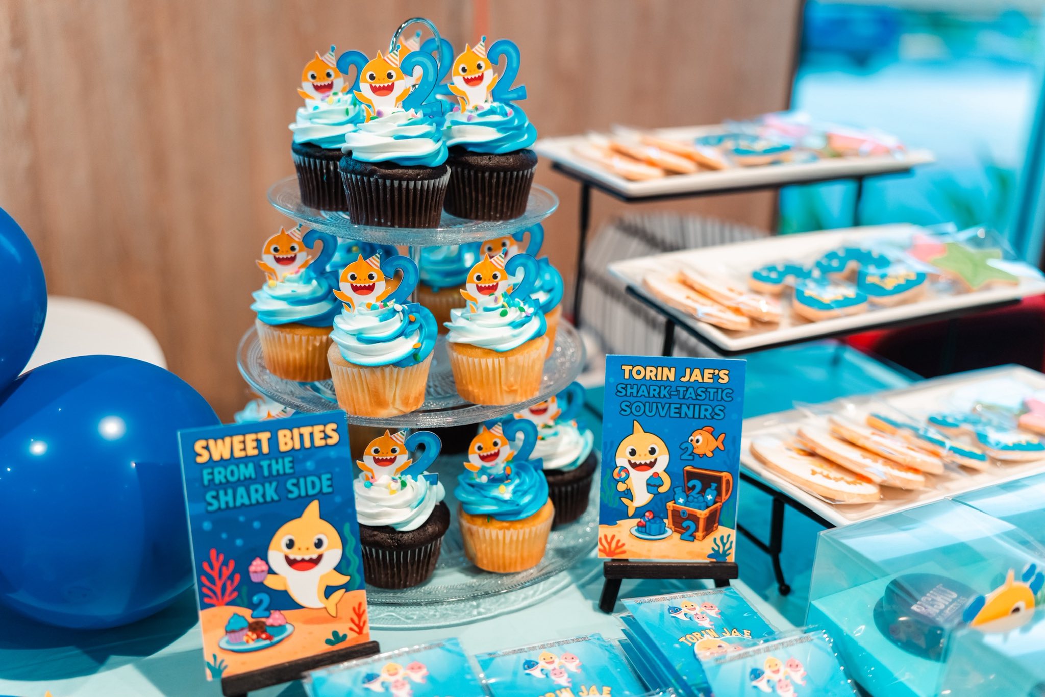 Tiered stand of baby shark theme cupcakes with blue and white frosting and number two cake toppers