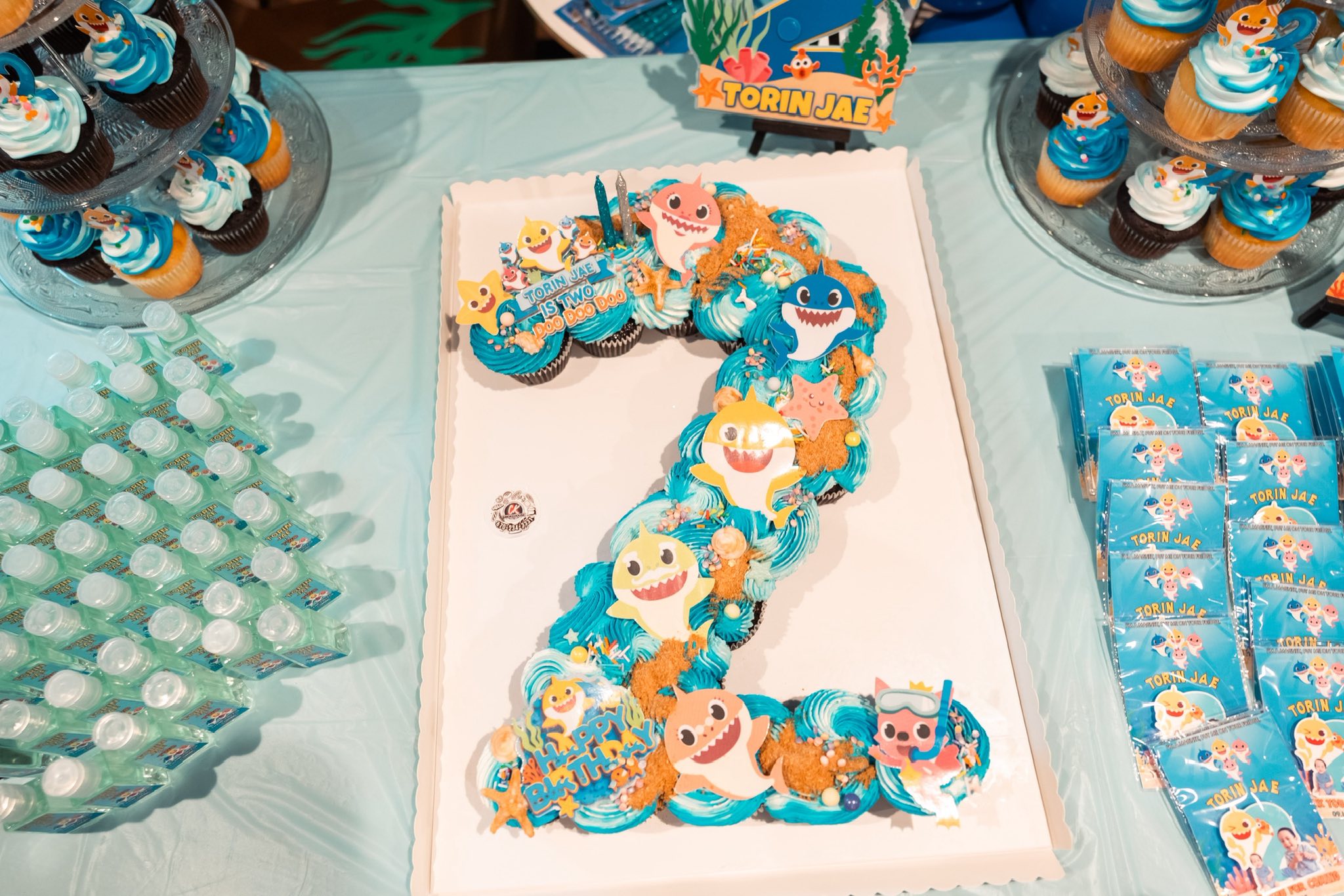Pull-apart cupcake cake in the shape of the number two decorated with Baby Shark toppers for a birthday party.