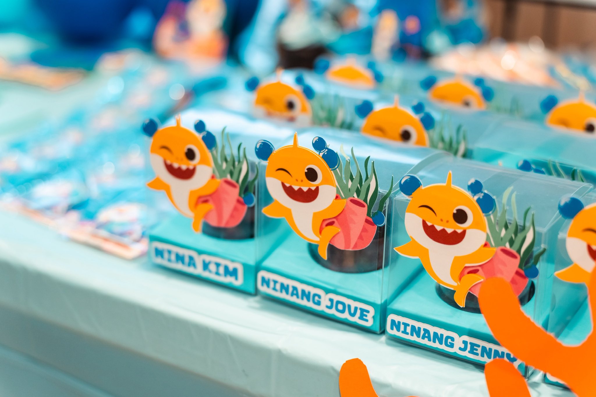 Baby Shark themed party favor boxes with personalized name tags on a display table.