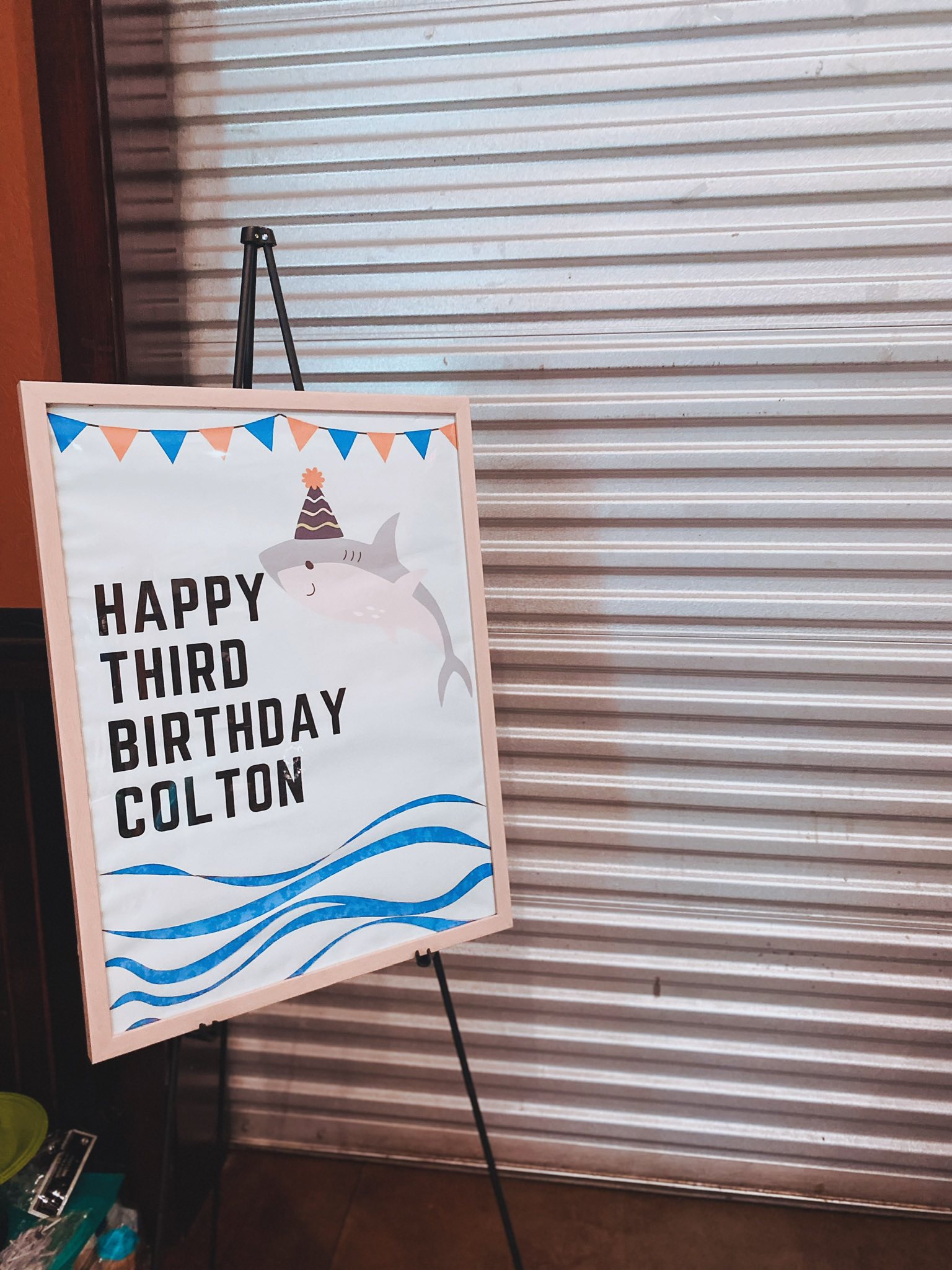 Shark-themed poster on an easel reading 'Happy Third Birthday Colton'