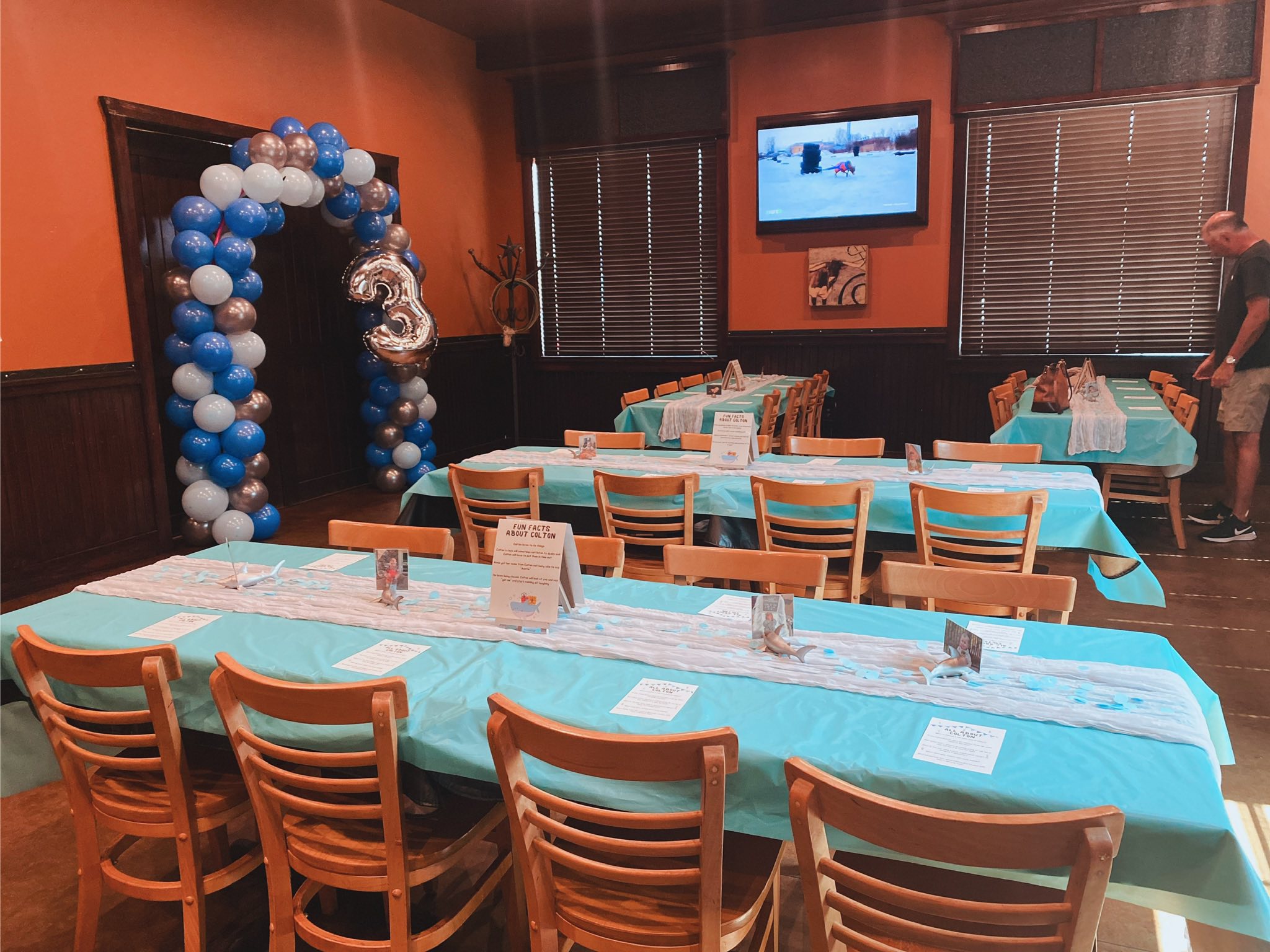 Dining room decorated for a third birthday party with blue and silver balloons and table settings.