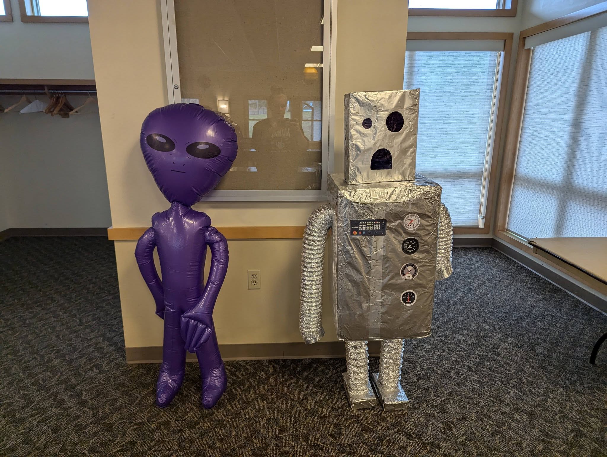 Inflatable purple alien standing next to a handmade silver foil robot.