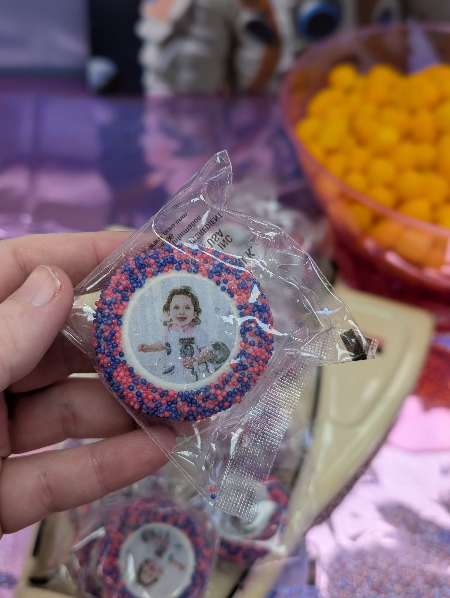 Custom cookie in clear packaging with a photo of a child and pink and purple sprinkles.