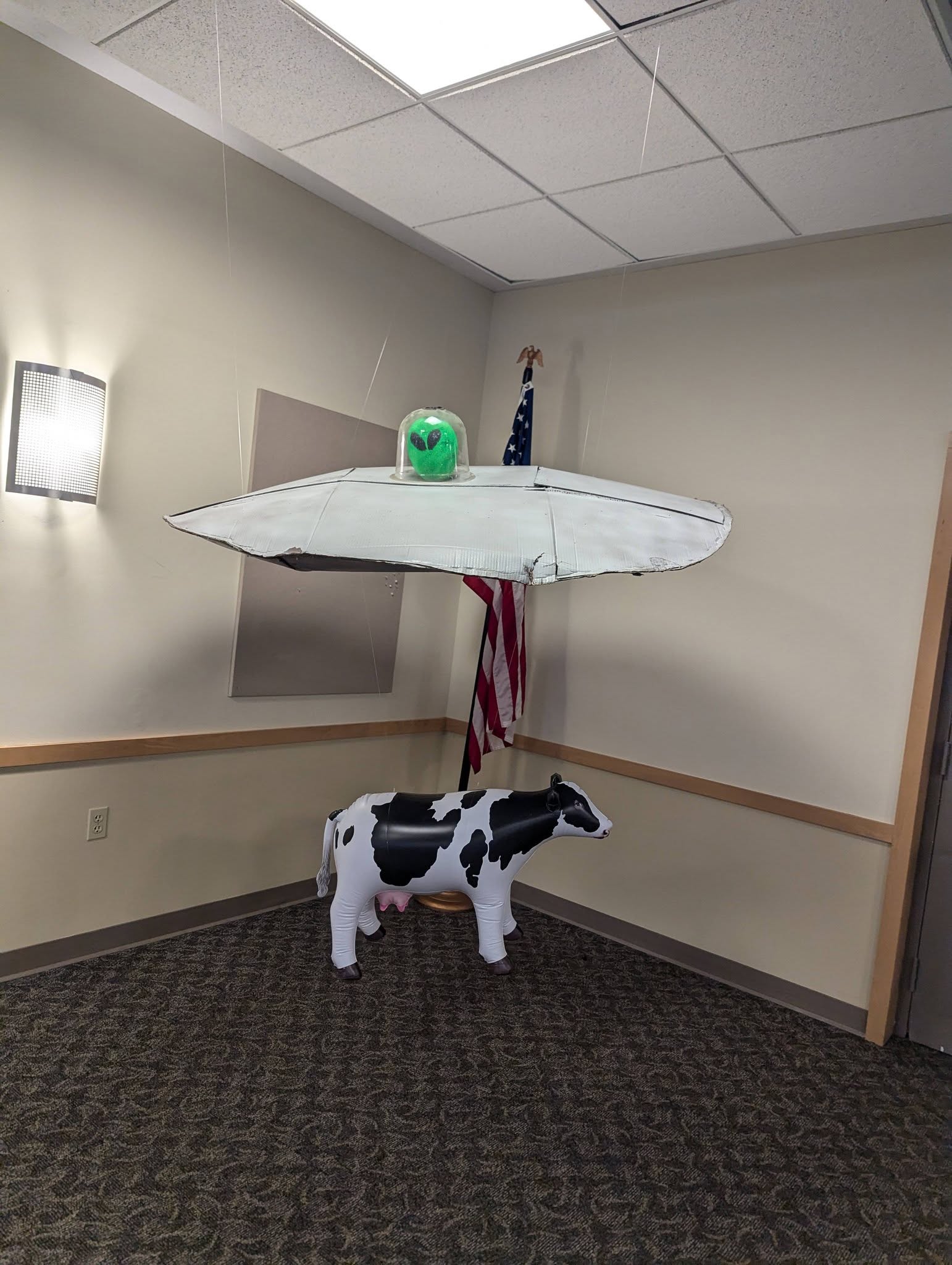 DIY UFO hanging over an inflatable cow decoration with an alien figure in the cockpit