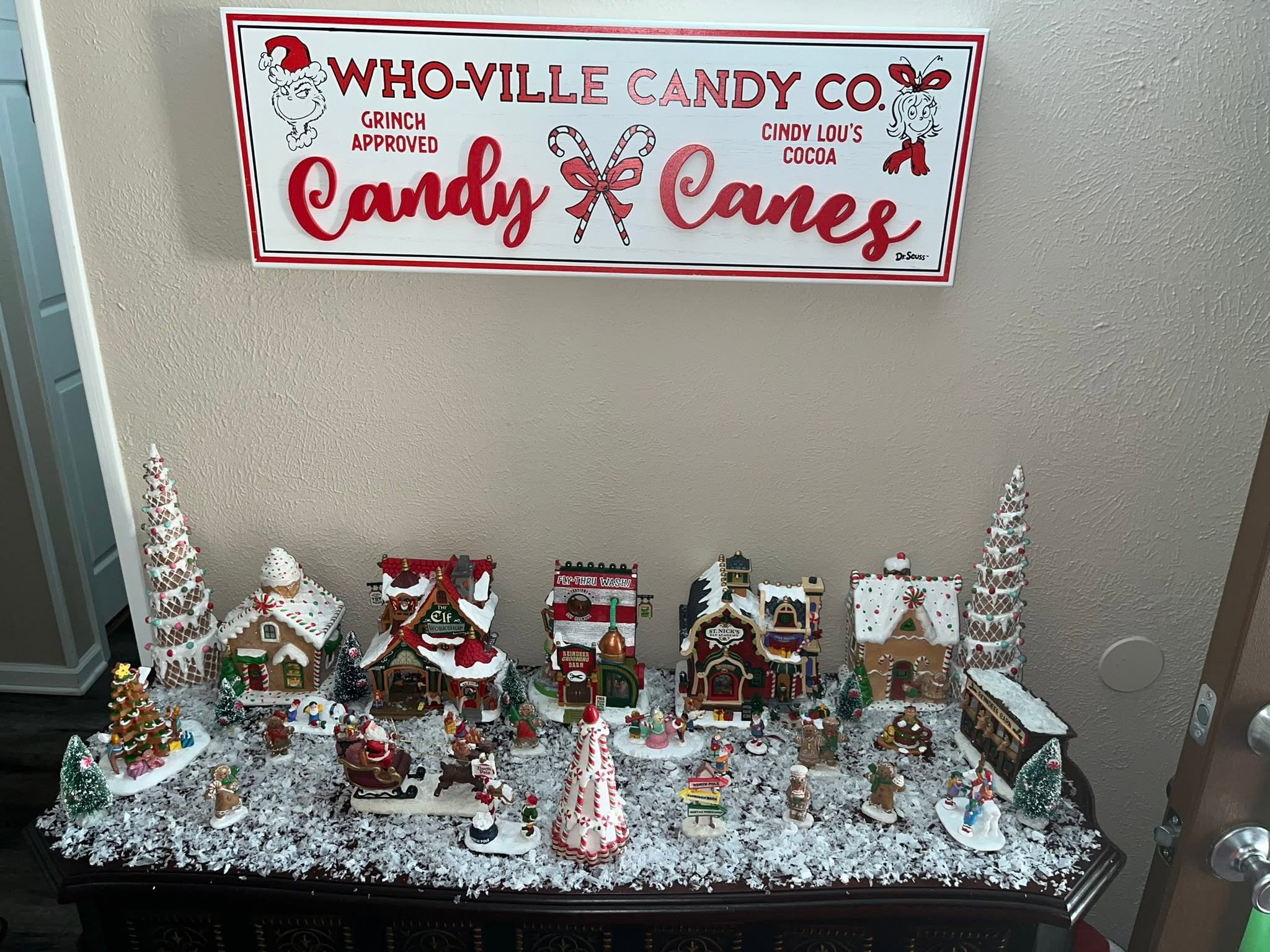 Tabletop Christmas village display with Who-Ville Candy Co sign featuring Grinch and Cindy Lou Who figures.
