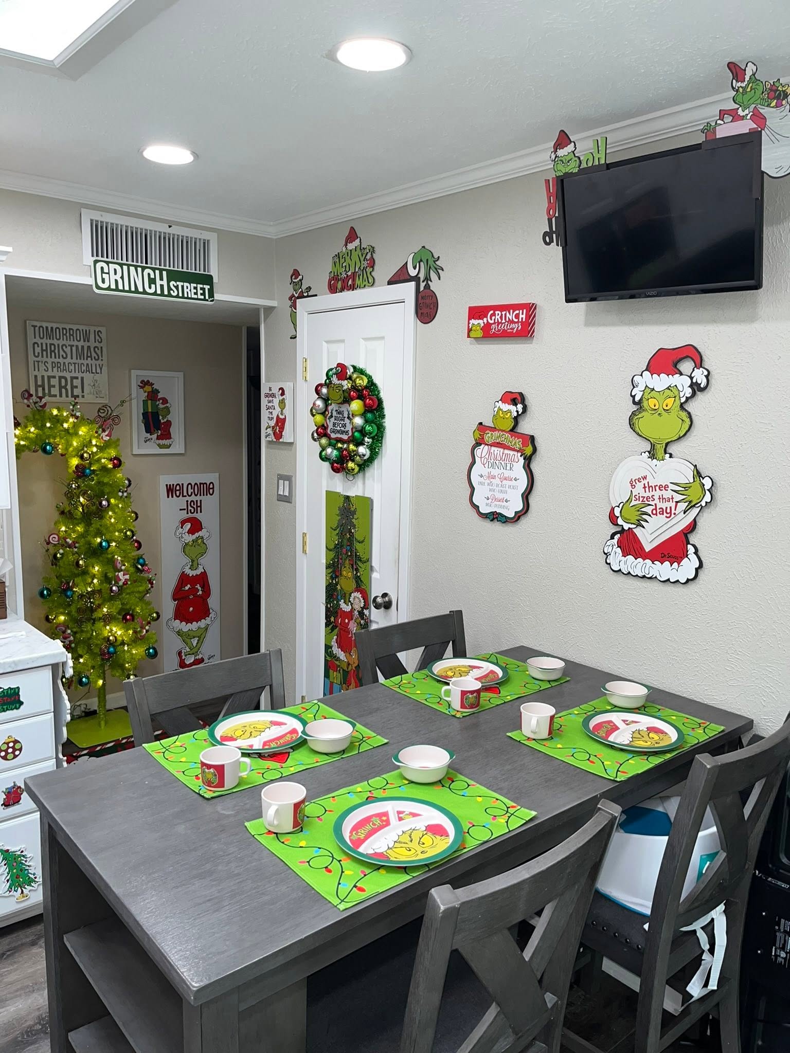 Dining room decorated with The Grinch themed tableware and wall signs for Christmas.