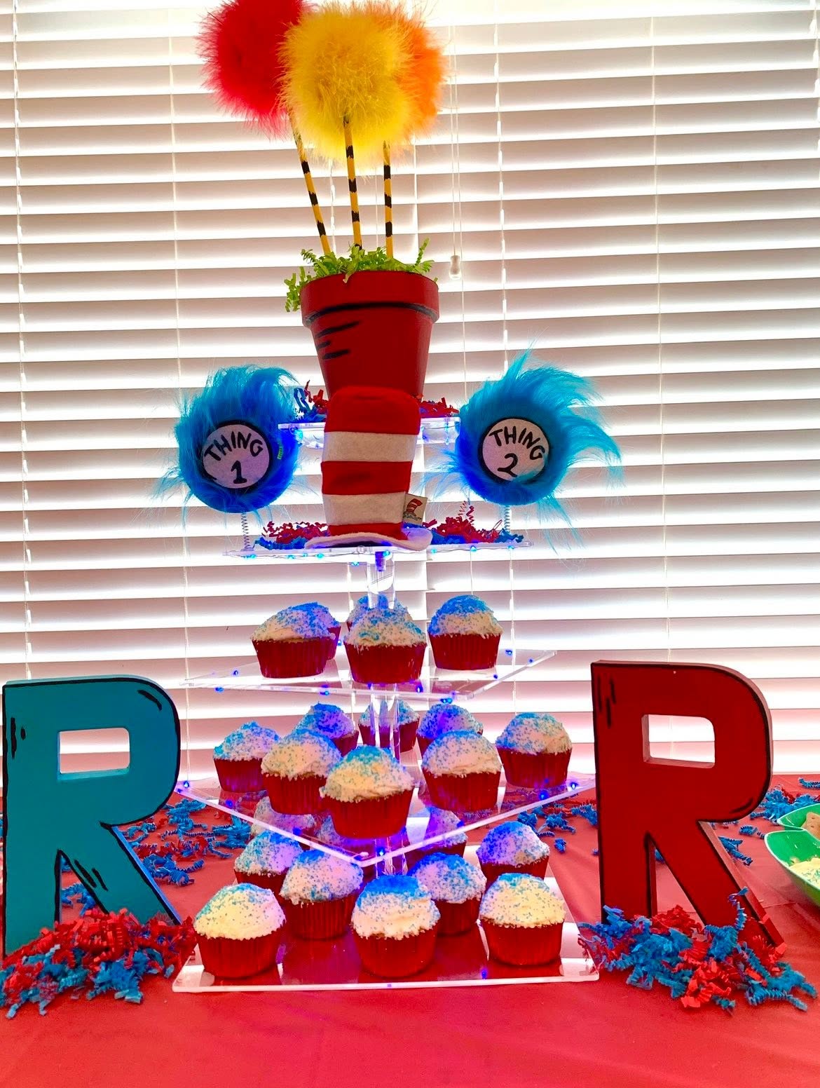 Dr. Seuss themed tiered cupcake stand decorated with Thing 1 and Thing 2 accents and a red and white striped hat.