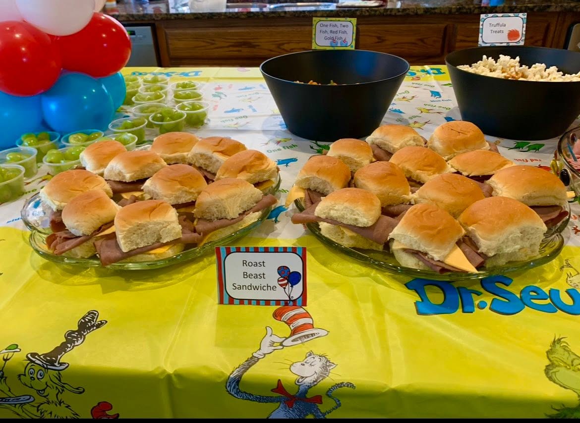 Platters of Roast Beast slider sandwiches at a Dr. Seuss themed party with snack bowls and green grapes.