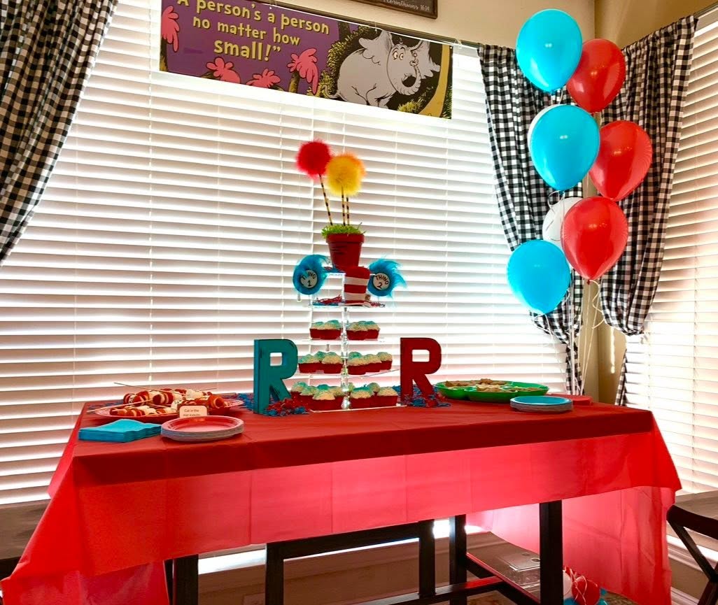 Dr. Seuss themed table with red tablecloth, cupcakes, and party decorations.