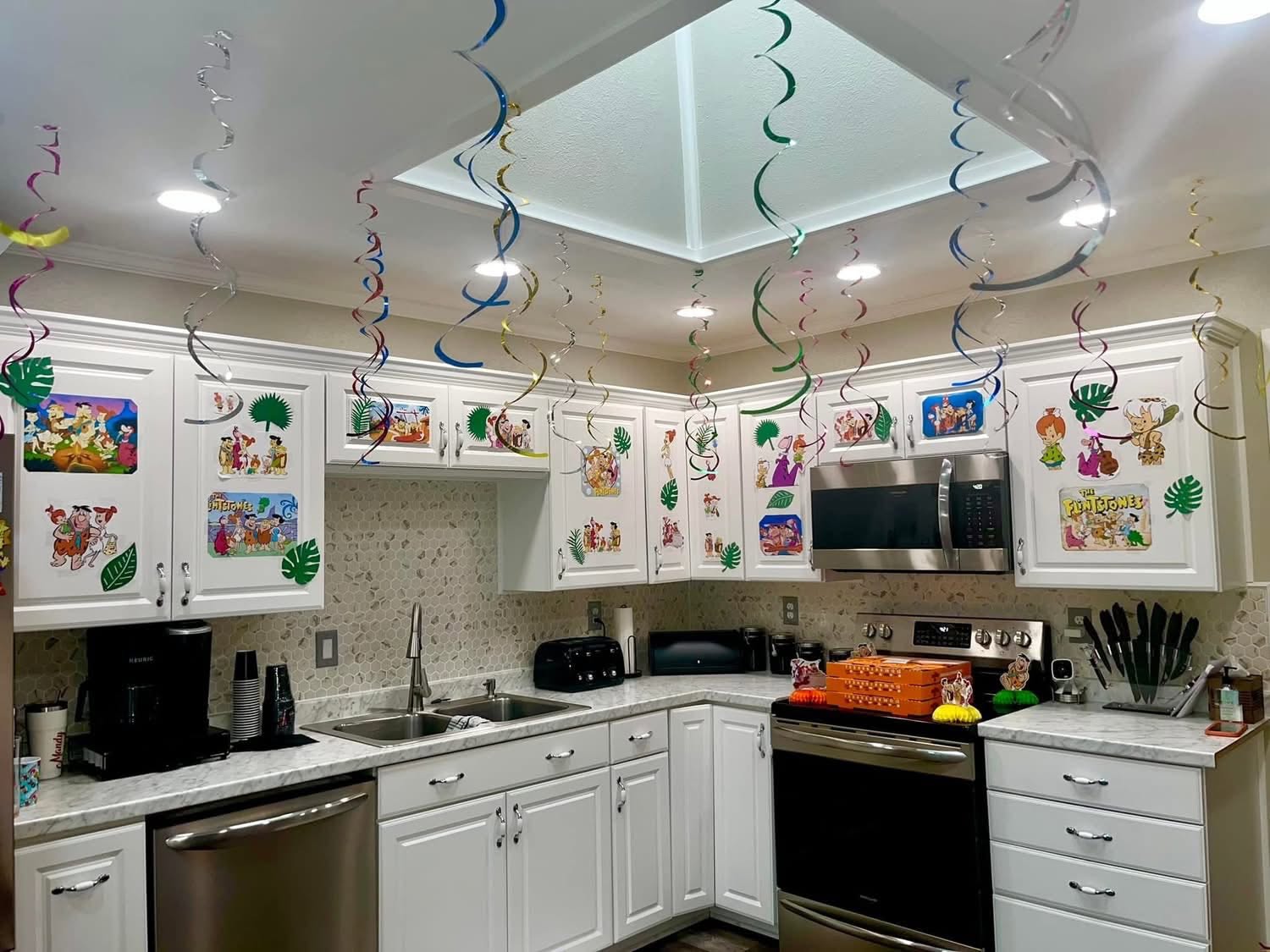 Kitchen decorated for a Flintstones themed party with character cutouts and hanging spiral streamers.