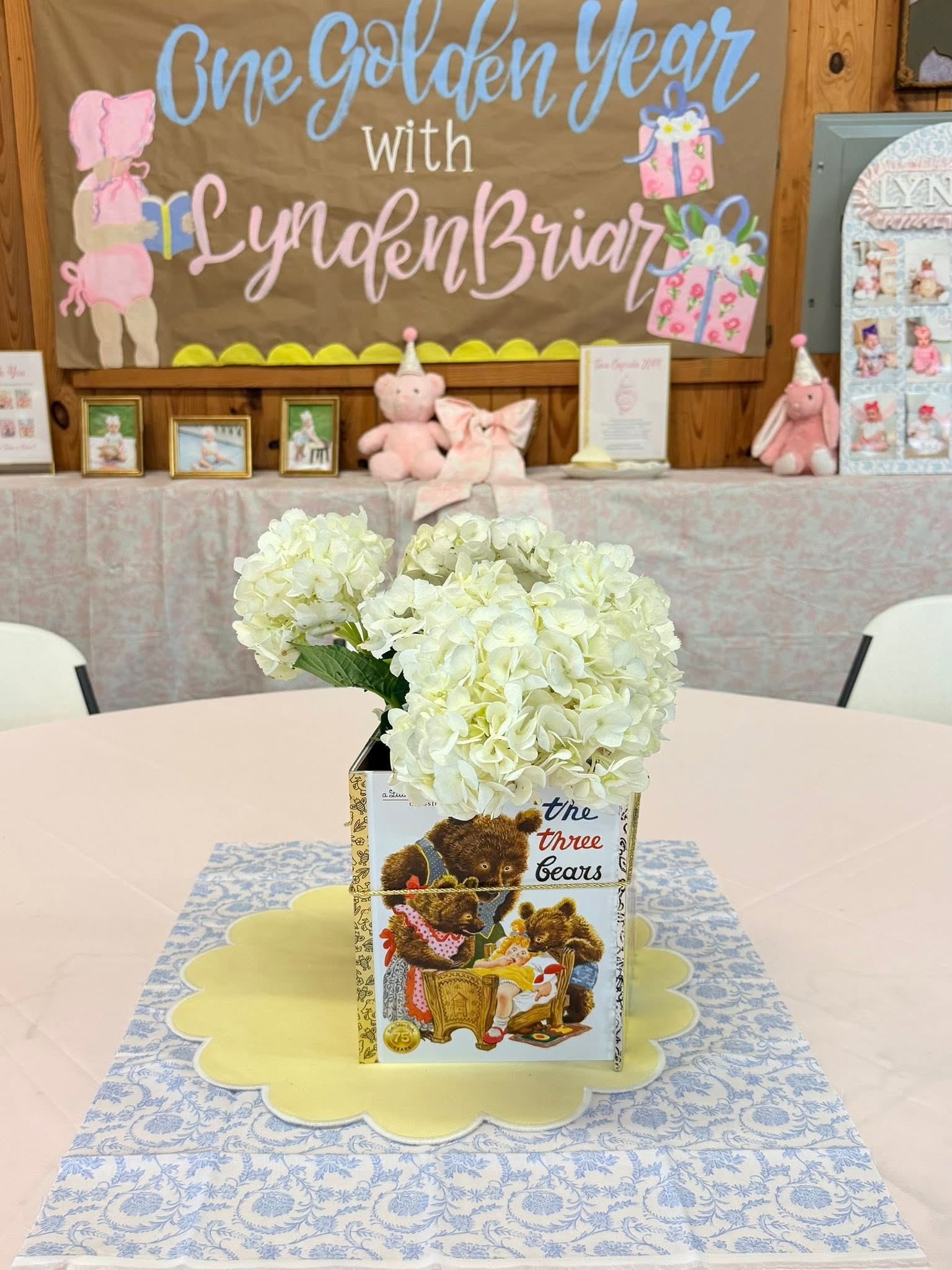 White hydrangea centerpiece in a Three Bears book vase on a birthday party table.
