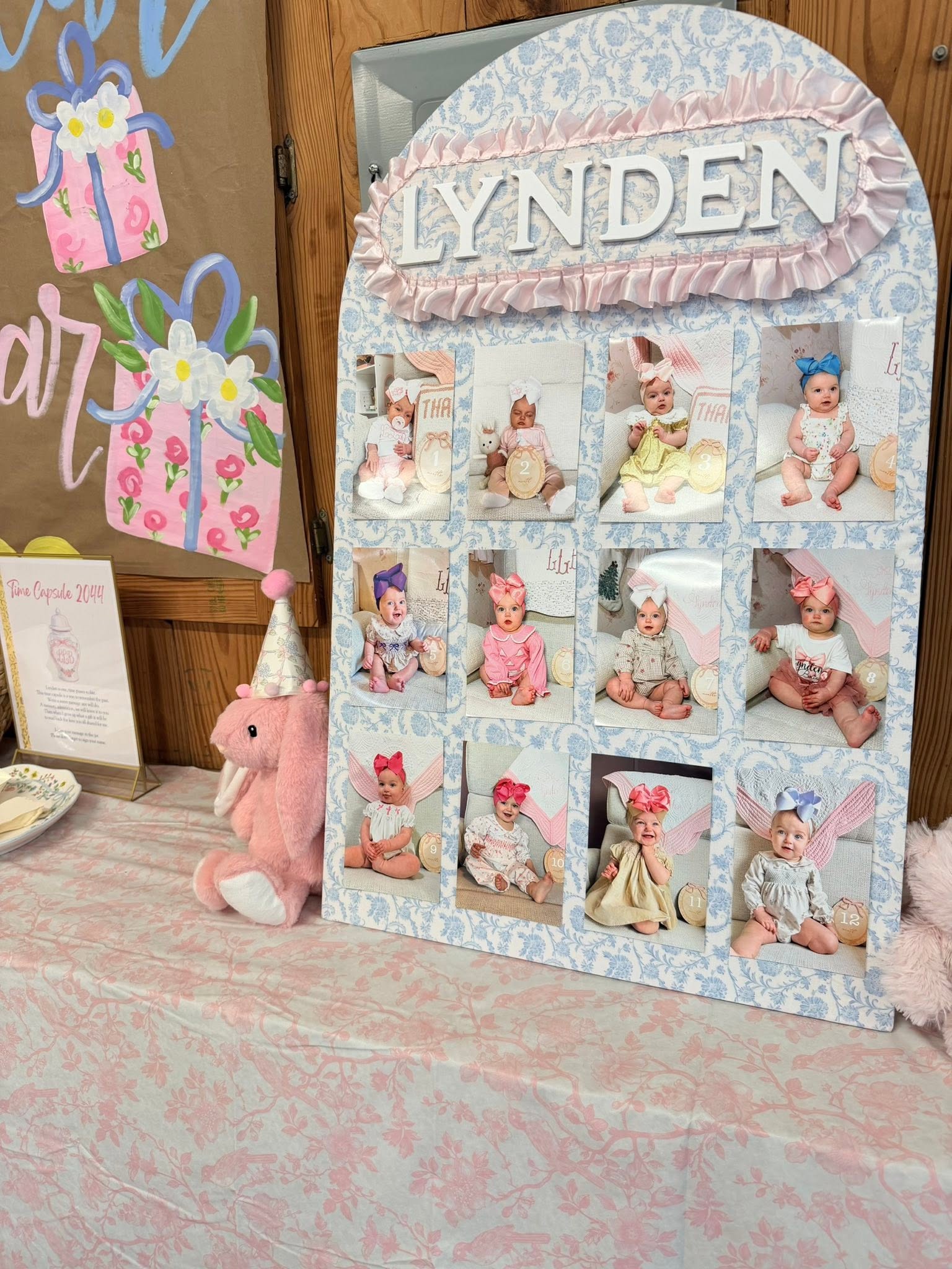 Custom baby monthly photo milestone board for Lynden decorated with blue floral pattern and pink ruffle trim.
