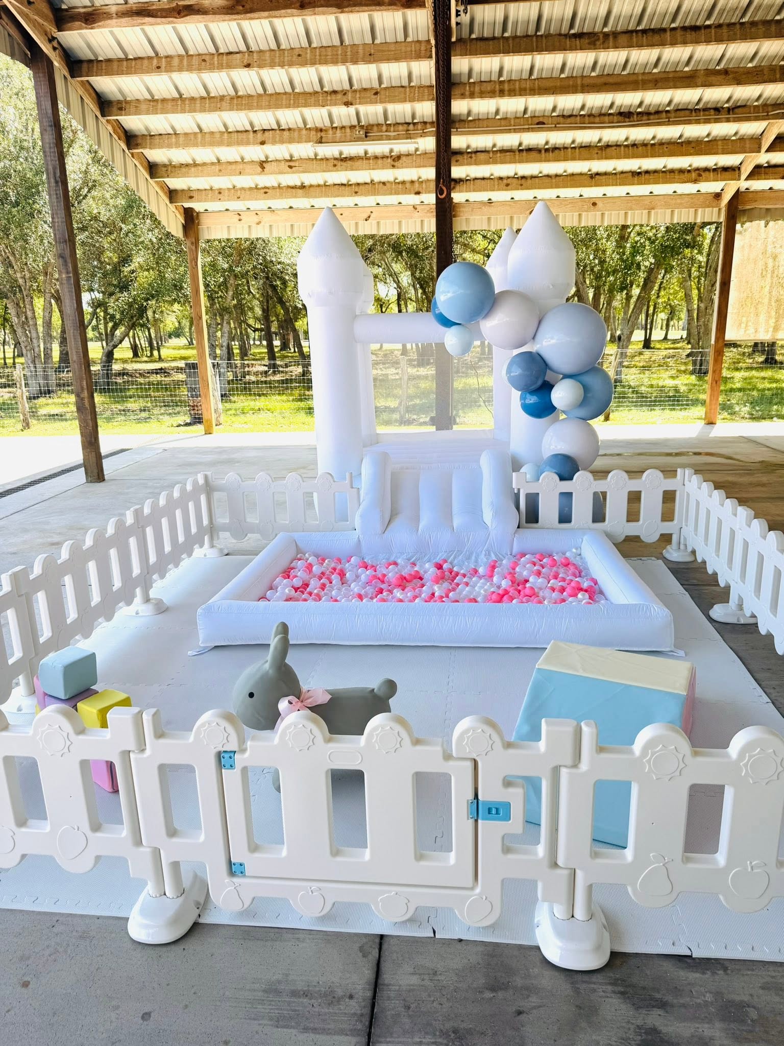 White inflatable bounce castle with a ball pit, slide, and surrounding play area for kids' parties