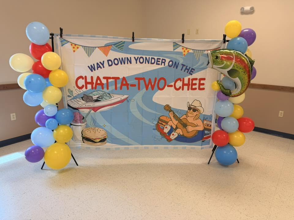 Birthday party backdrop with Way Down Yonder on the Chatta-Two-Chee signage surrounded by colorful balloons