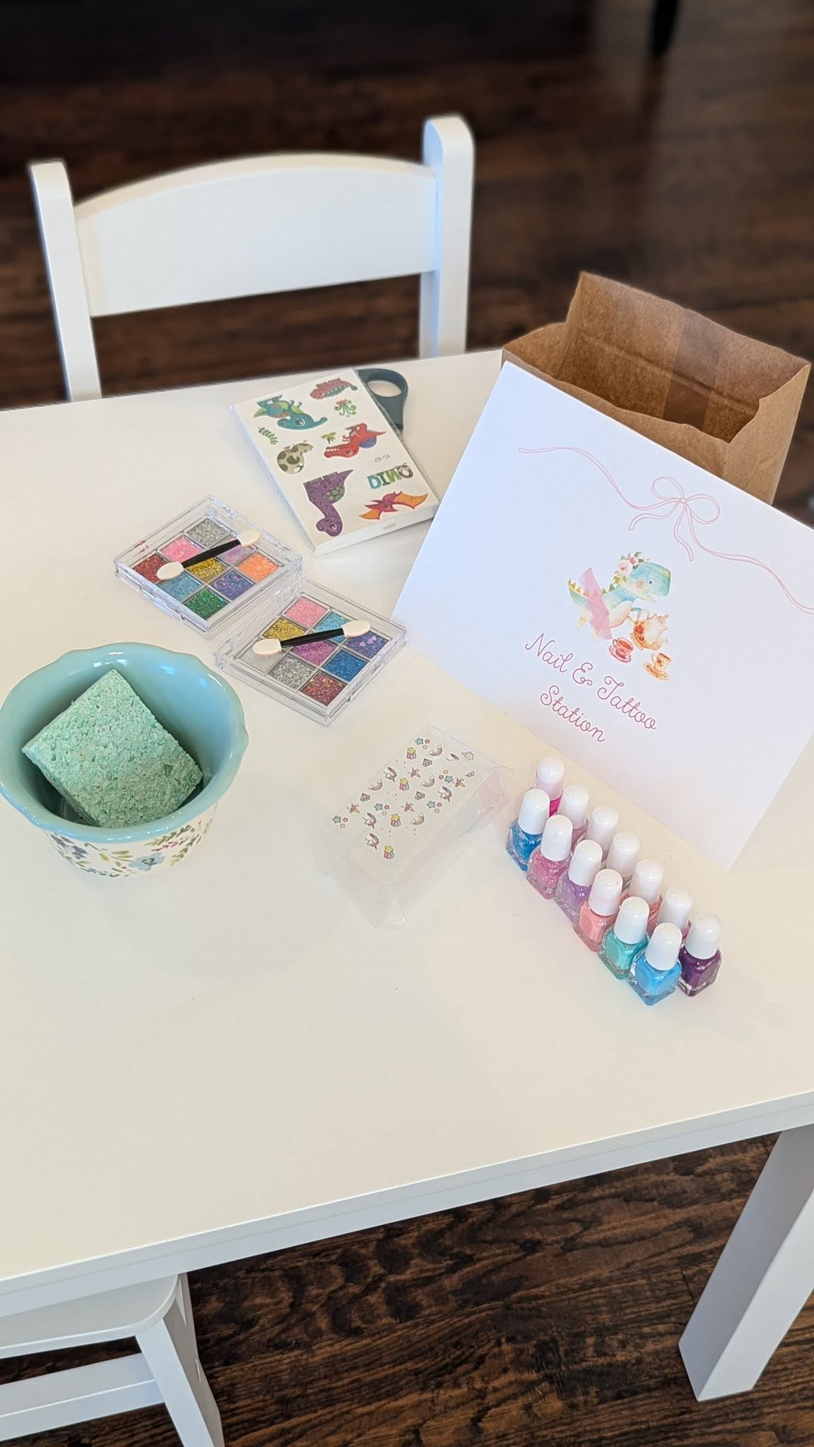 Kids' party nail and tattoo station with colorful nail polish, glitter eyeshadows, and dinosaur temporary tattoos.