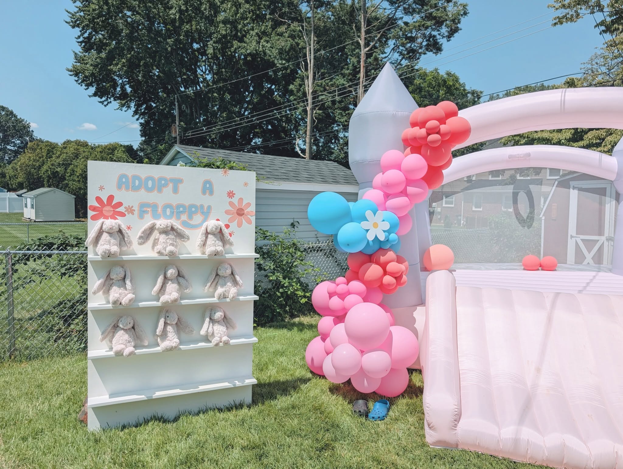 Adopt a Floppy display shelf featuring plush bunny toys next to a pink balloon-decorated bounce house.