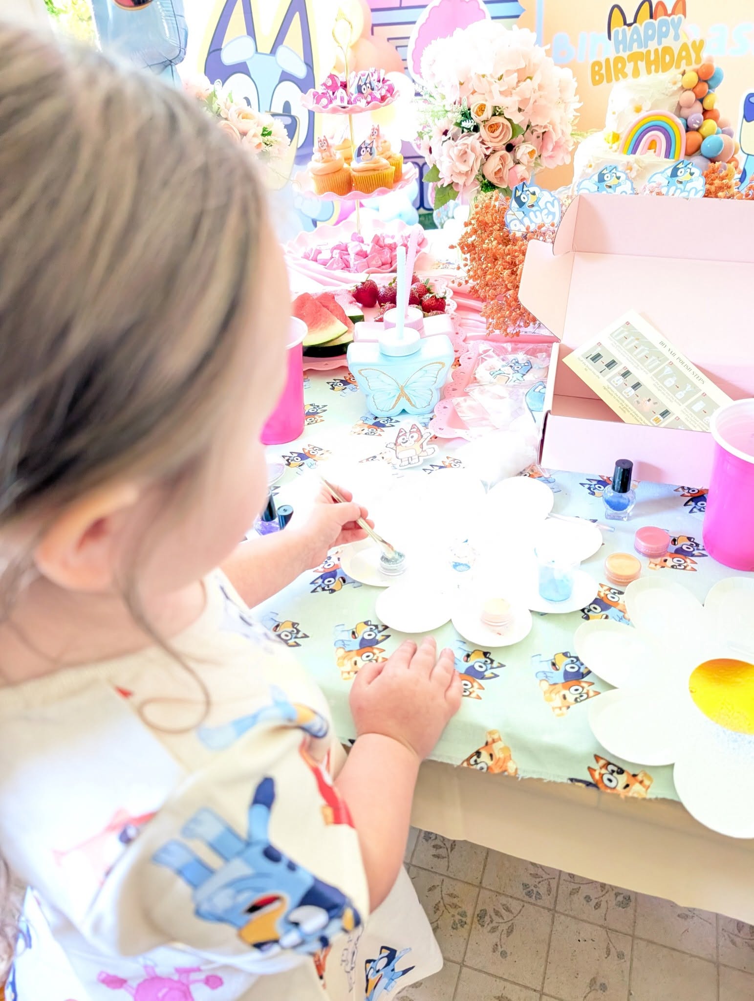 Young girl painting at a Bluey-themed birthday party table.
