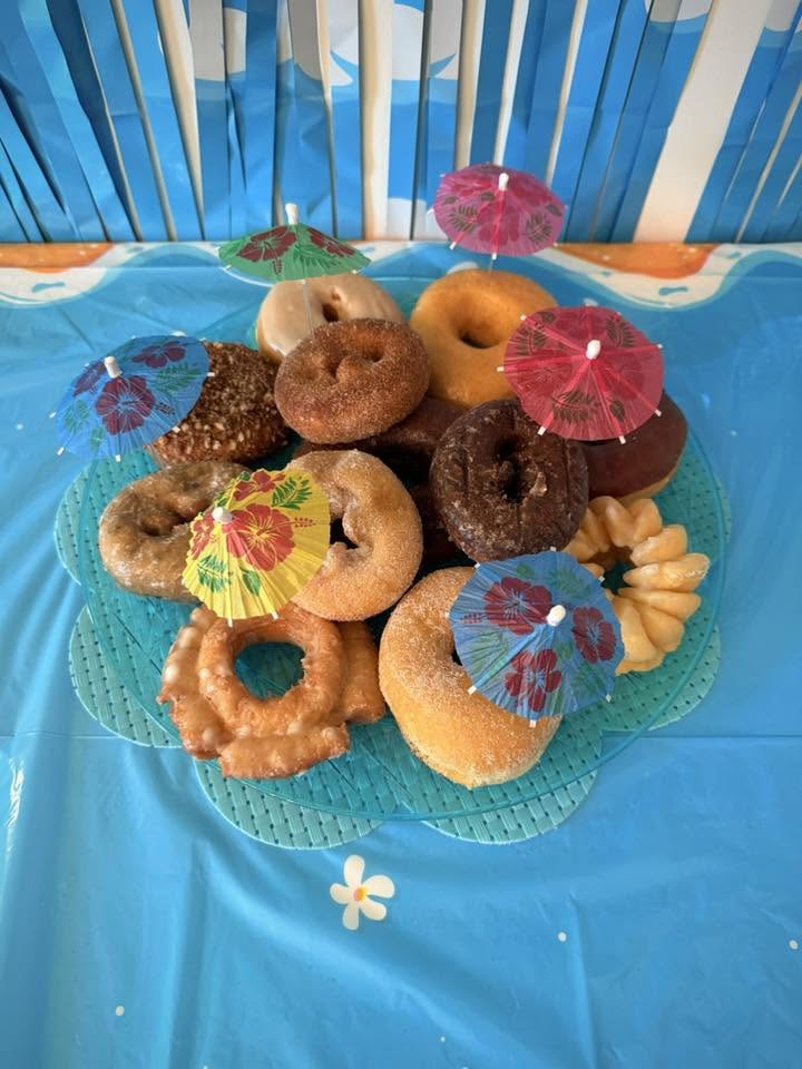 Platter of assorted donuts decorated with colorful tropical cocktail umbrellas