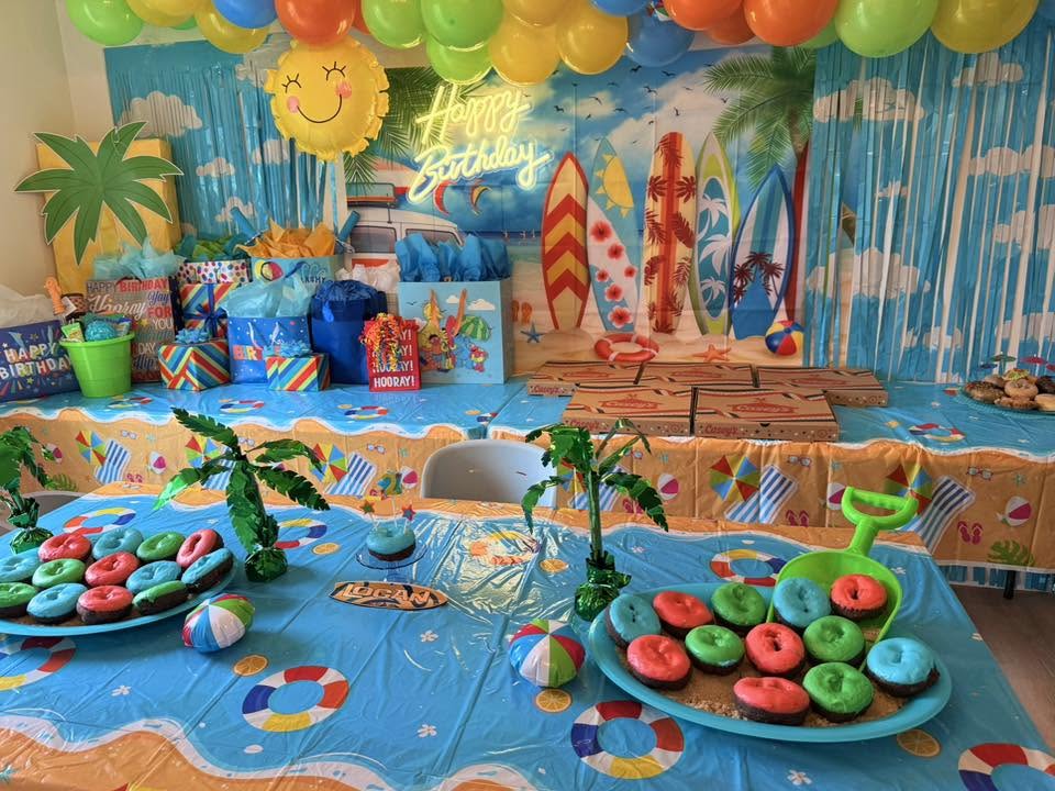 Surfer-themed birthday party decorations with colorful balloons, surfboards, and beach-themed snacks.