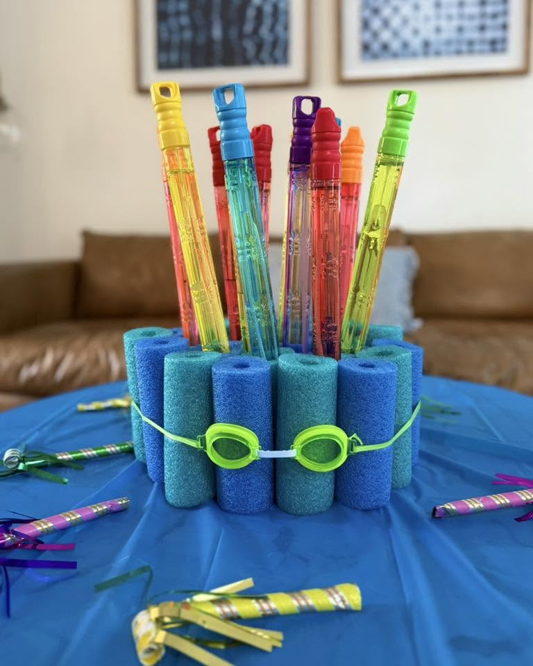 Table centerpiece made of blue foam pool noodles organized as a canister holding assorted colorful bubble wands