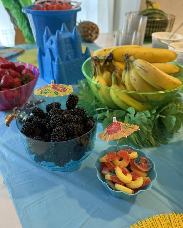 Bowls of fresh strawberries, bananas, blackberries, and gummy peach rings decorated with small tiki umbrellas