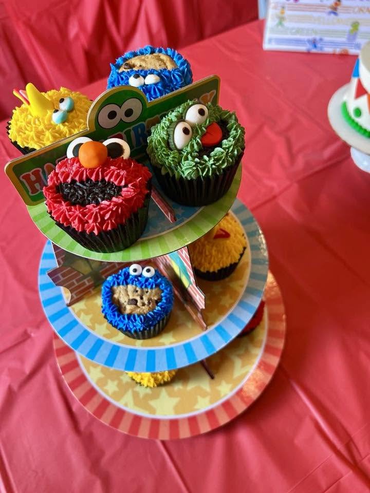 Sesame Street-themed cupcake stand featuring Elmo, Cookie Monster, Big Bird, and Oscar the Grouch cupcakes.