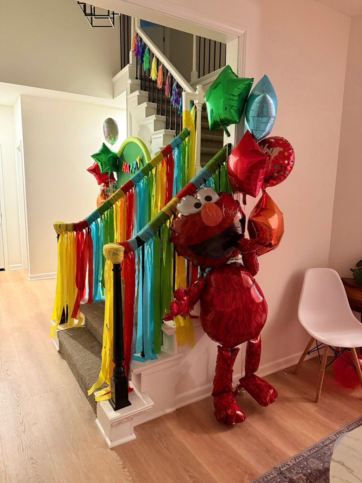 Staircase decorated for a birthday with colorful streamers and a large Elmo foil balloon.