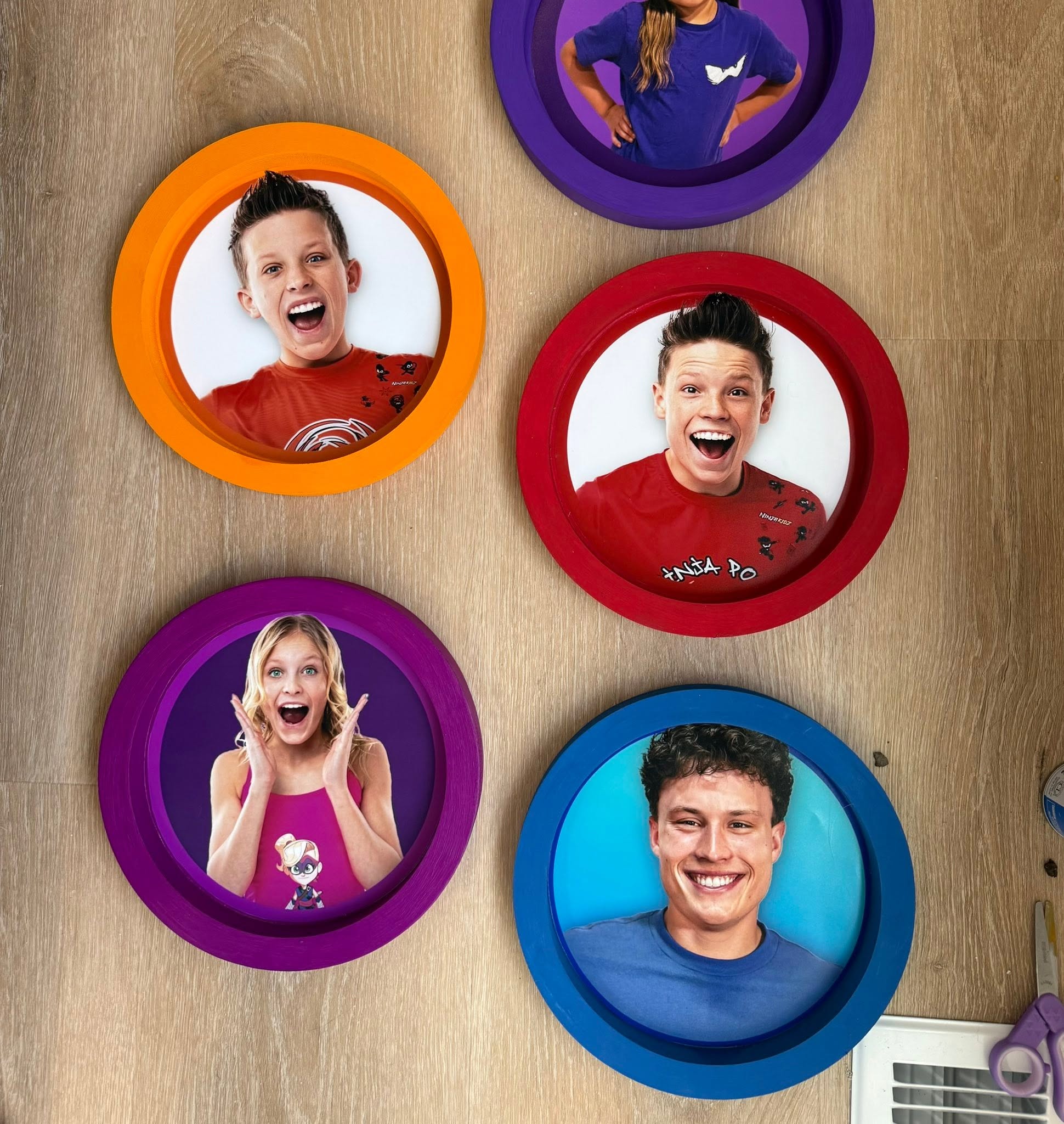 Collection of round colorful wall frames featuring photos of Ninja Kidz cast members.