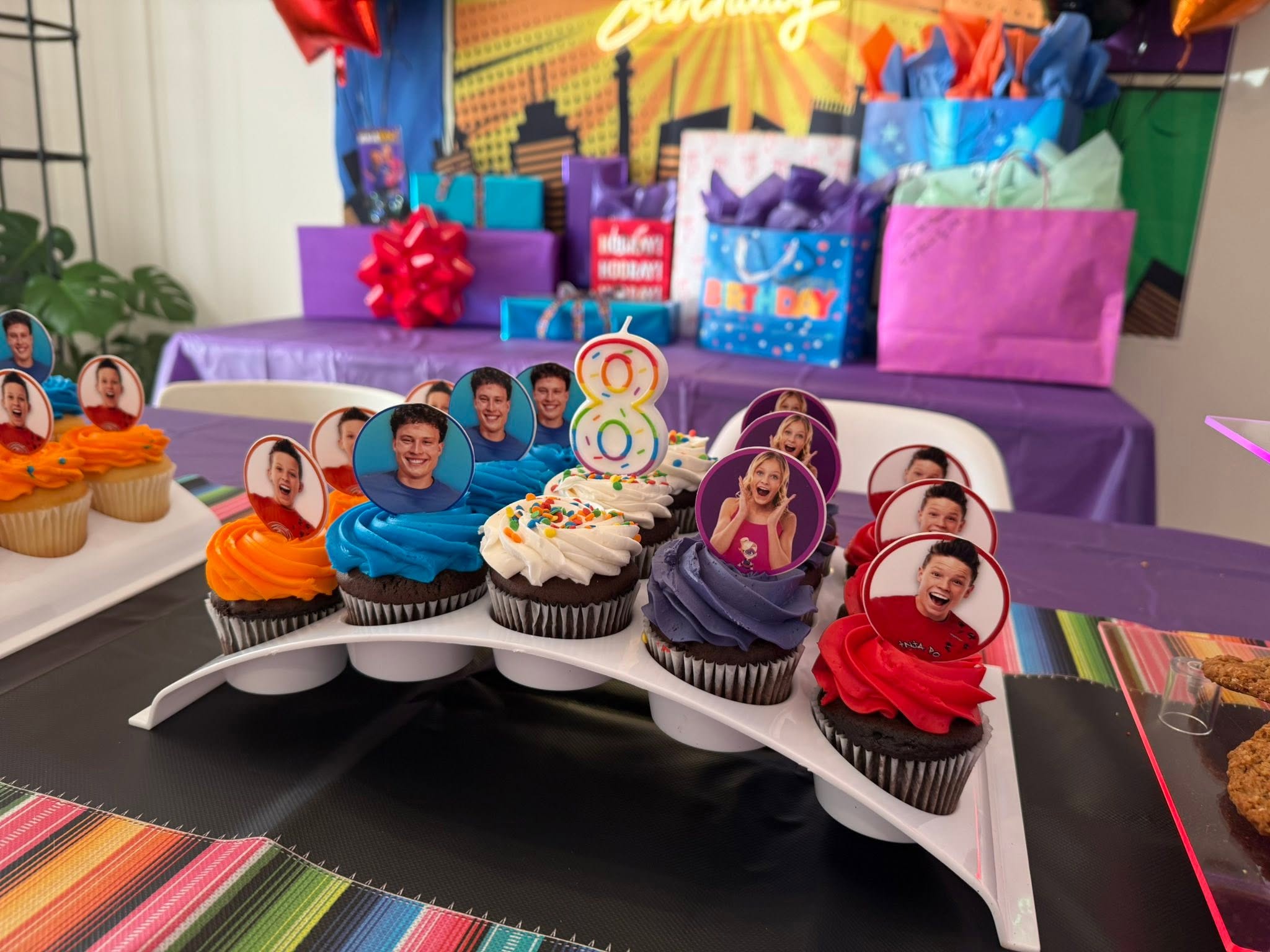 Cupcakes decorated with colorful frosting and custom photo toppers for an eighth birthday celebration.